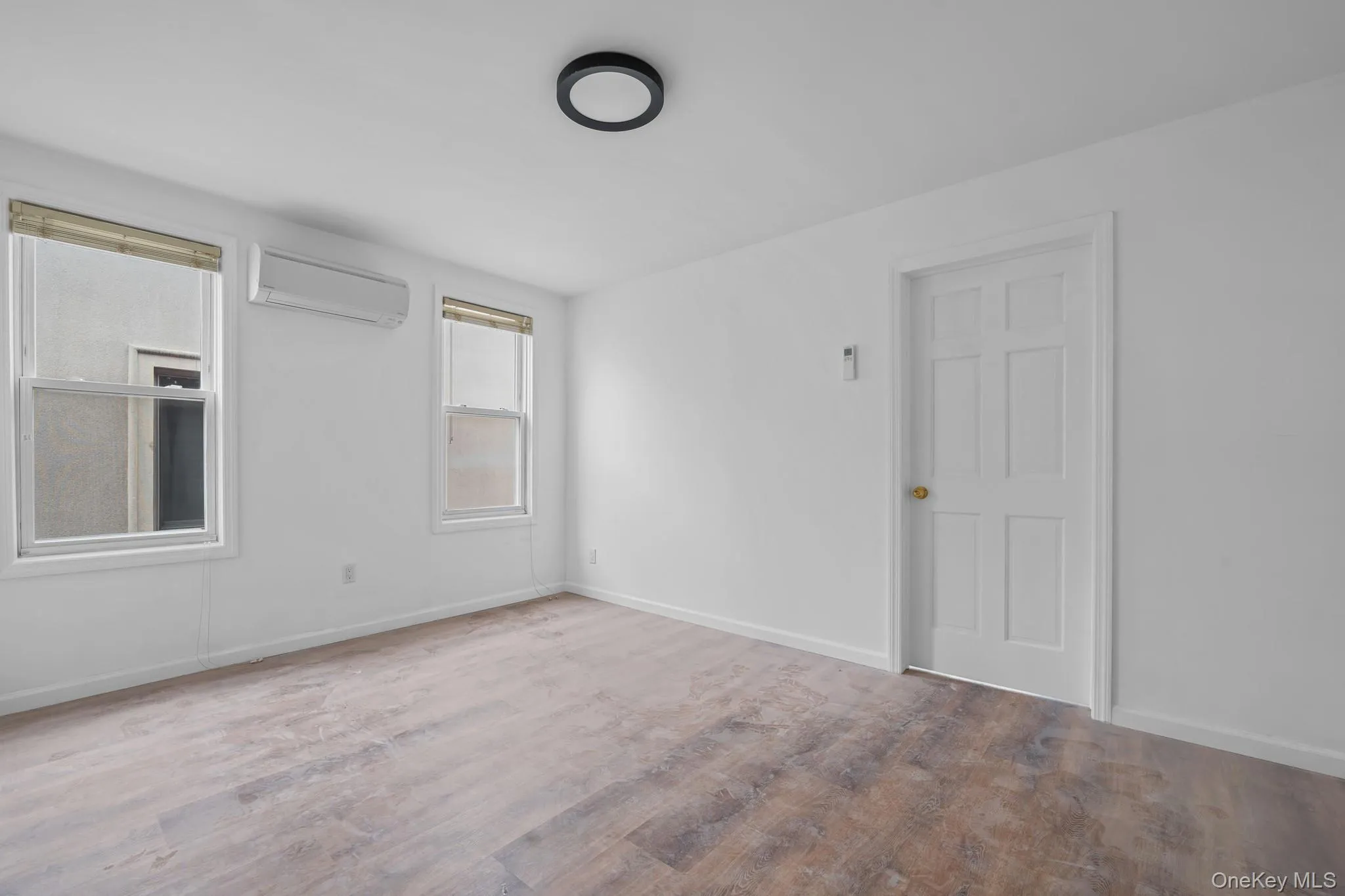 Empty room with an AC wall unit and wood finished floors Empty room with an AC wall unit and wood finished floors