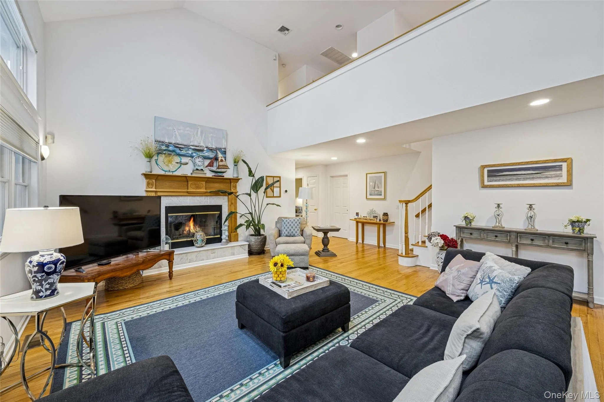 Living area featuring stairway, wood finished floors, a premium fireplace, and high vaulted ceiling Living area featuring stairway, wood finished floors, a premium fireplace, and high vaulted ceiling