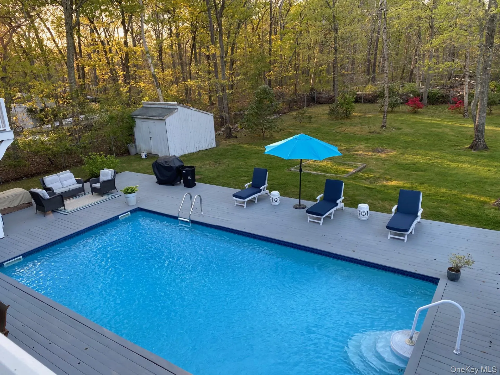 Outdoor pool featuring a deck, a yard, a grill, and a storage shed Outdoor pool featuring a deck, a yard, a grill, and a storage shed