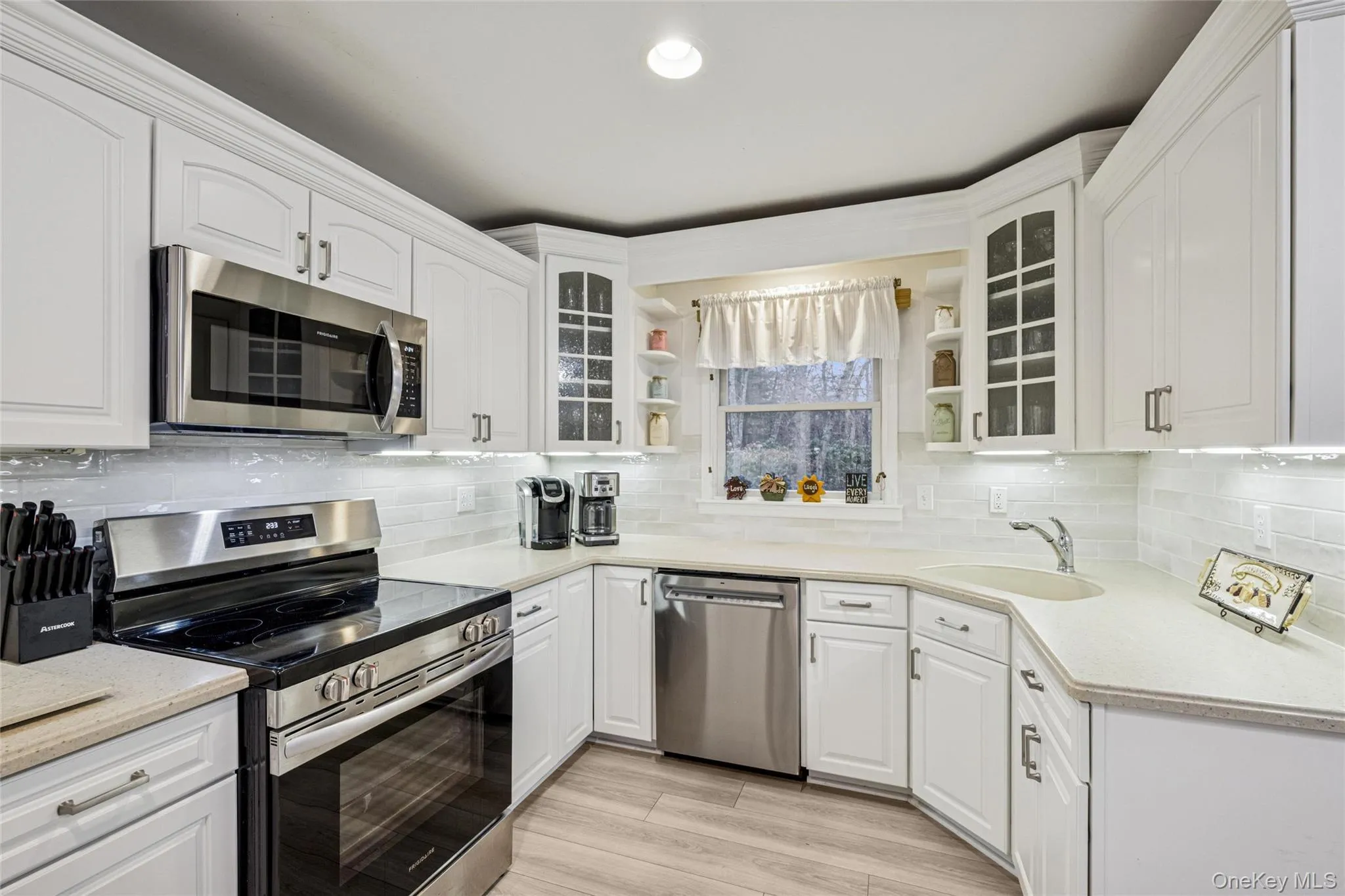 Kitchen featuring stainless steel appliances, open shelves, glass insert cabinets, white cabinets, and recessed lighting Kitchen featuring stainless steel appliances, open shelves, glass insert cabinets, white cabinets, and recessed lighting