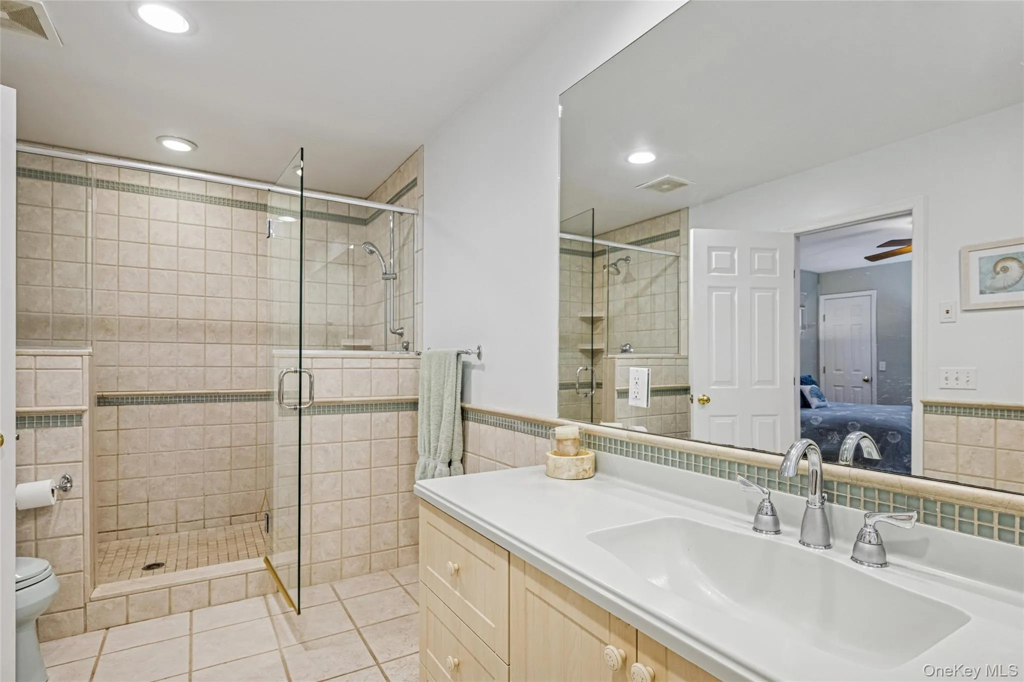 Ensuite bathroom featuring vanity, a stall shower, tile walls, light tile patterned floors, and recessed lighting Ensuite bathroom featuring vanity, a stall shower, tile walls, light tile patterned floors, and recessed lighting