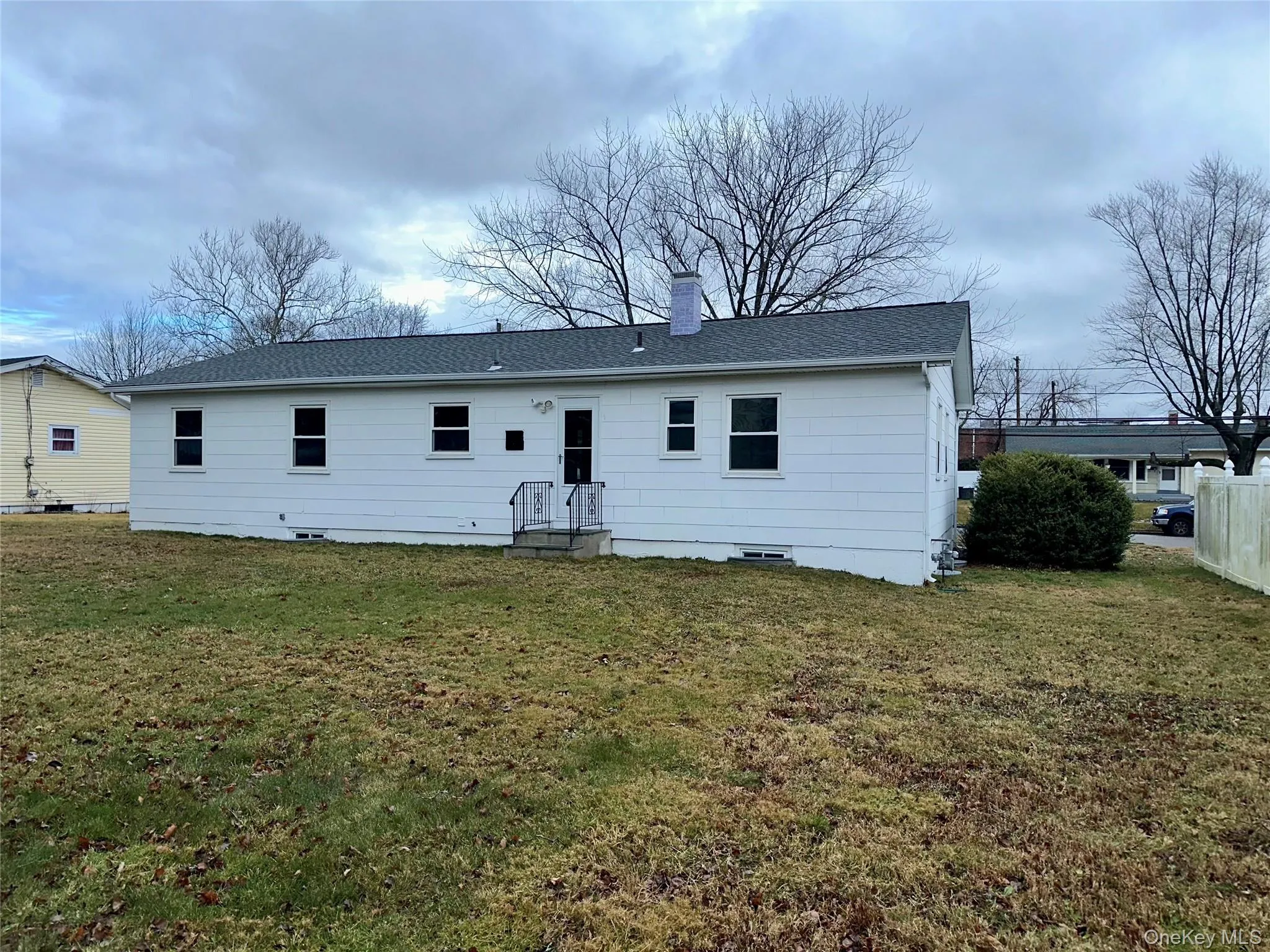 Back of house with a chimney, a yard, and a shingled roof Back of house with a chimney, a yard, and a shingled roof