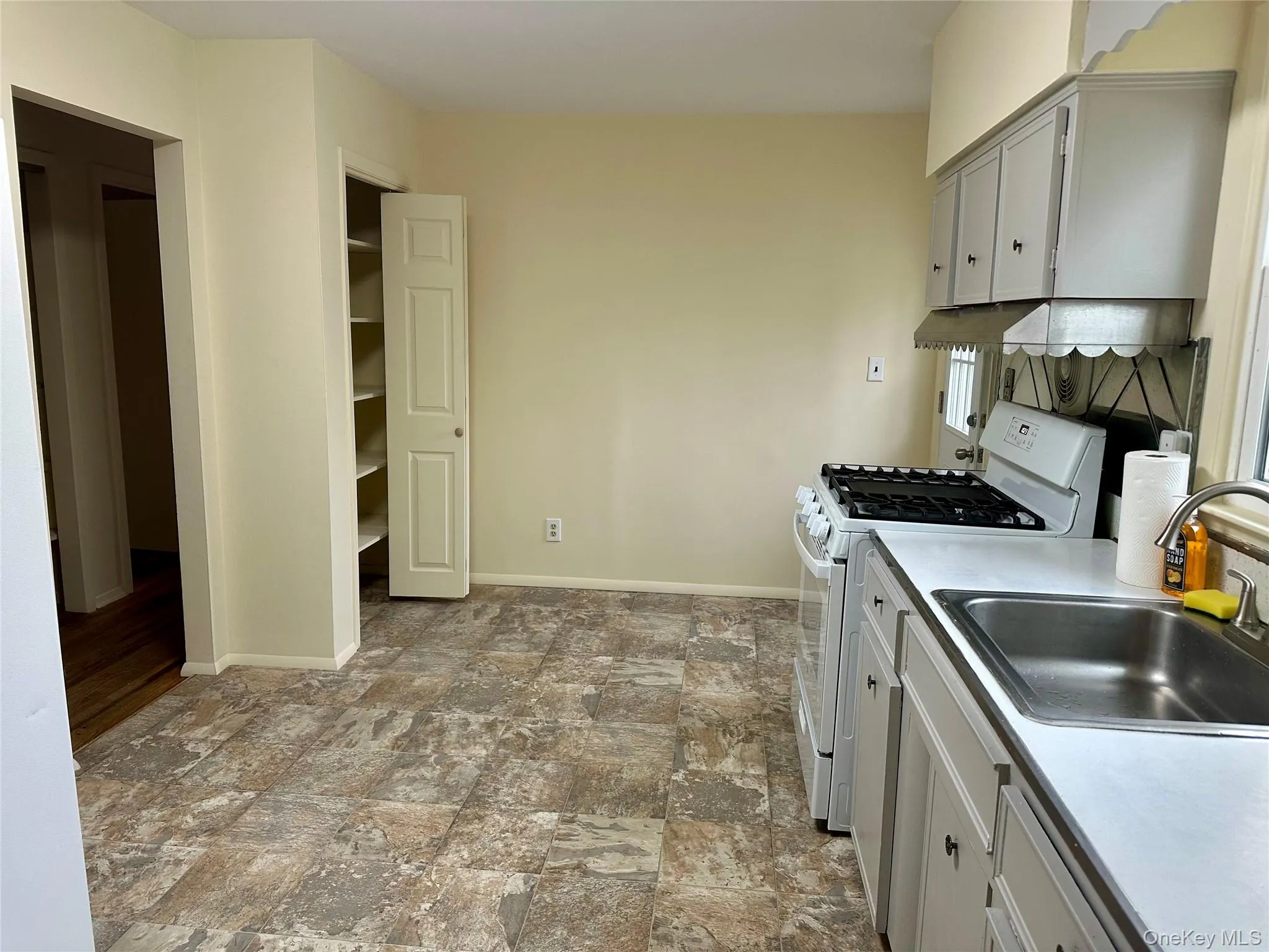 Kitchen featuring white range with gas cooktop, light countertops, and stone finish flooring Kitchen featuring white range with gas cooktop, light countertops, and stone finish flooring