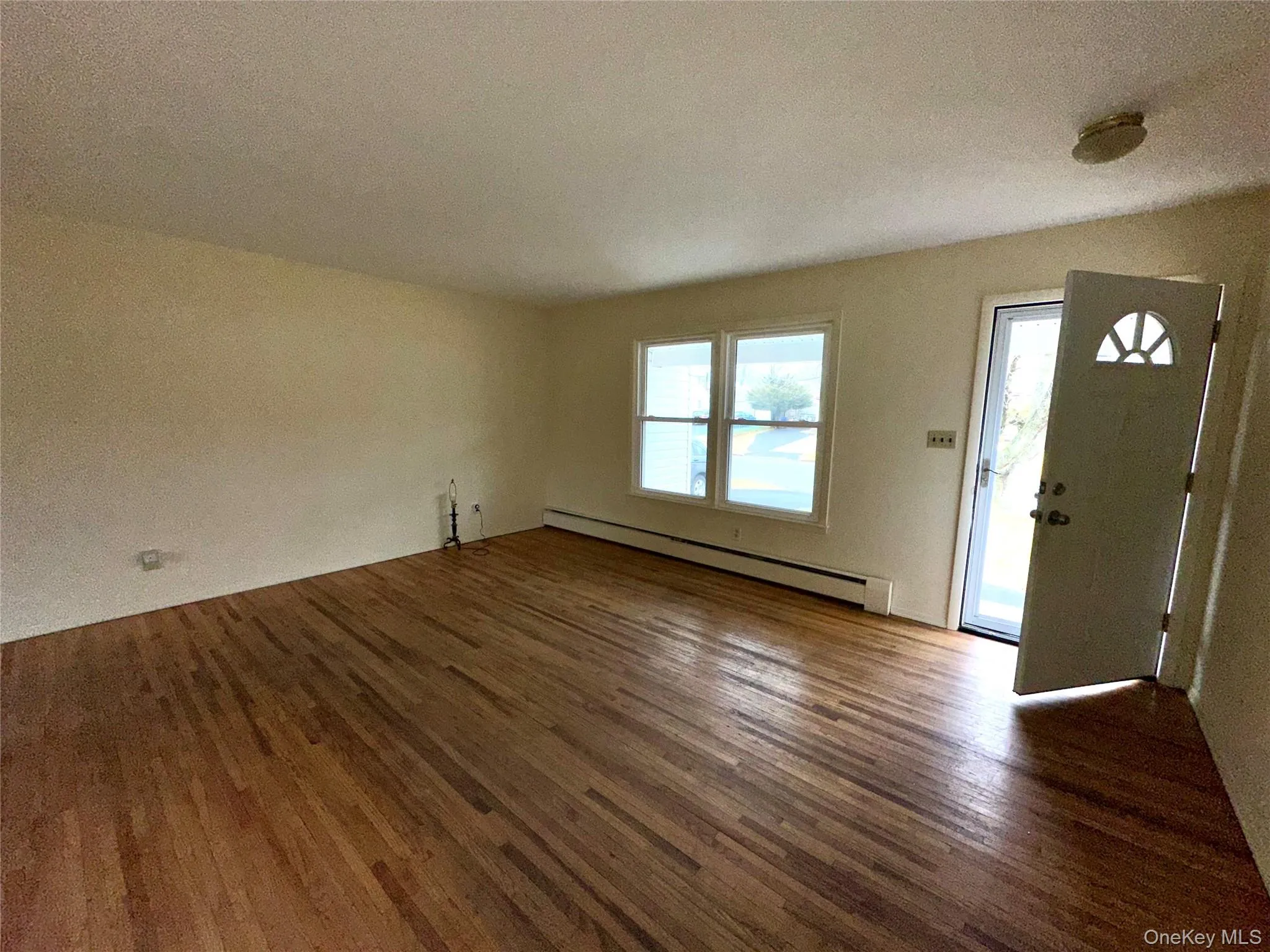 Foyer with baseboard heating, dark wood-type flooring, and a textured ceiling Foyer with baseboard heating, dark wood-type flooring, and a textured ceiling