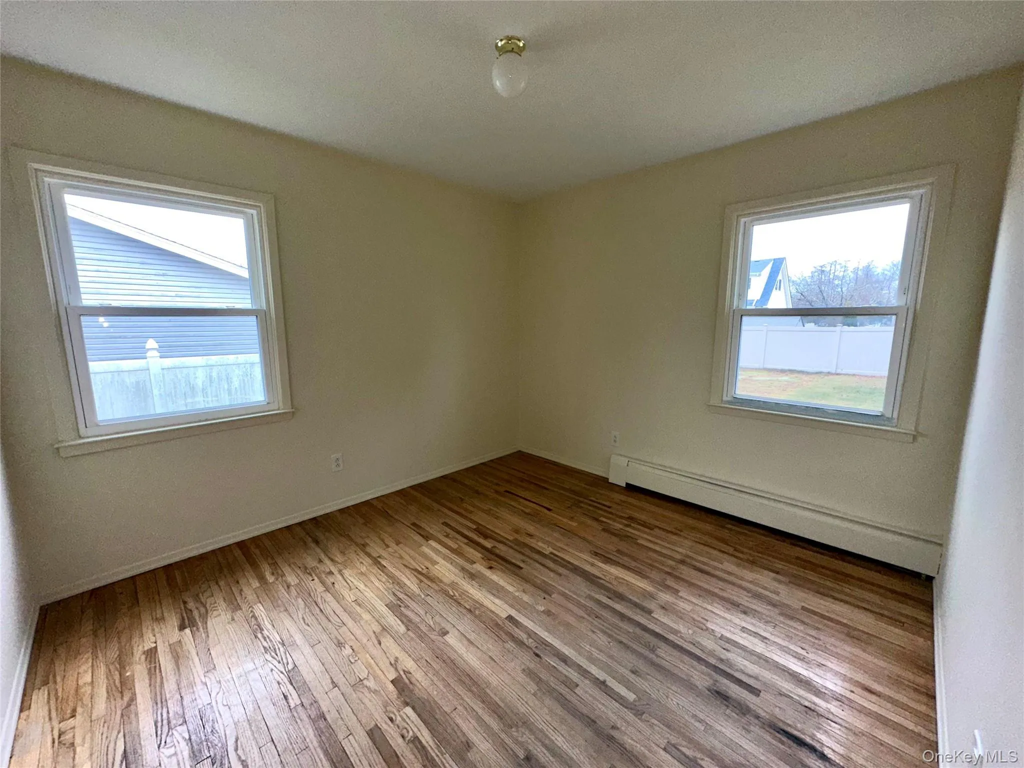 Unfurnished room featuring a baseboard radiator, light wood-style flooring, and healthy amount of natural light Unfurnished room featuring a baseboard radiator, light wood-style flooring, and healthy amount of natural light