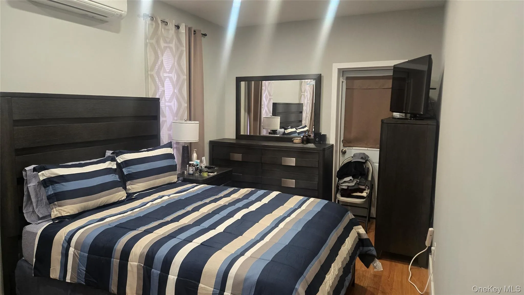 Bedroom featuring a wall mounted AC, wood finished floors, and a closet Bedroom featuring a wall mounted AC, wood finished floors, and a closet