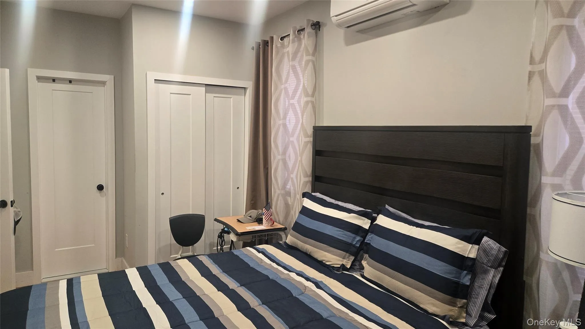 Bedroom featuring a wall mounted AC and a closet Bedroom featuring a wall mounted AC and a closet