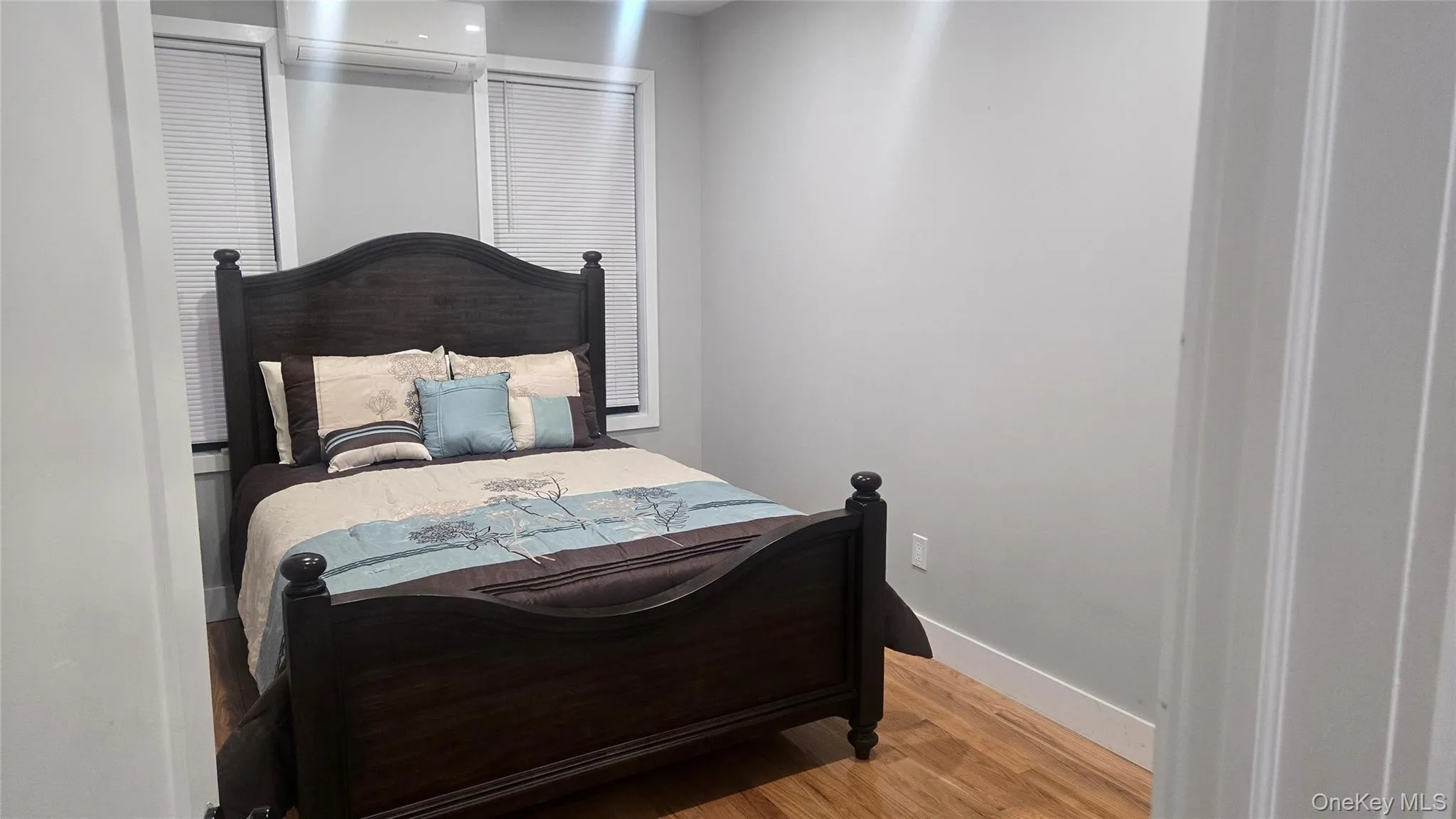 Bedroom with a wall unit AC and light wood-style flooring Bedroom with a wall unit AC and light wood-style flooring