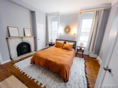 Bedroom featuring a fireplace and wood finished floors Bedroom featuring a fireplace and wood finished floors