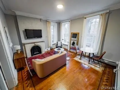 Living area with a fireplace, healthy amount of natural light, ornamental molding, and wood finished floors Living area with a fireplace, healthy amount of natural light, ornamental molding, and wood finished floors