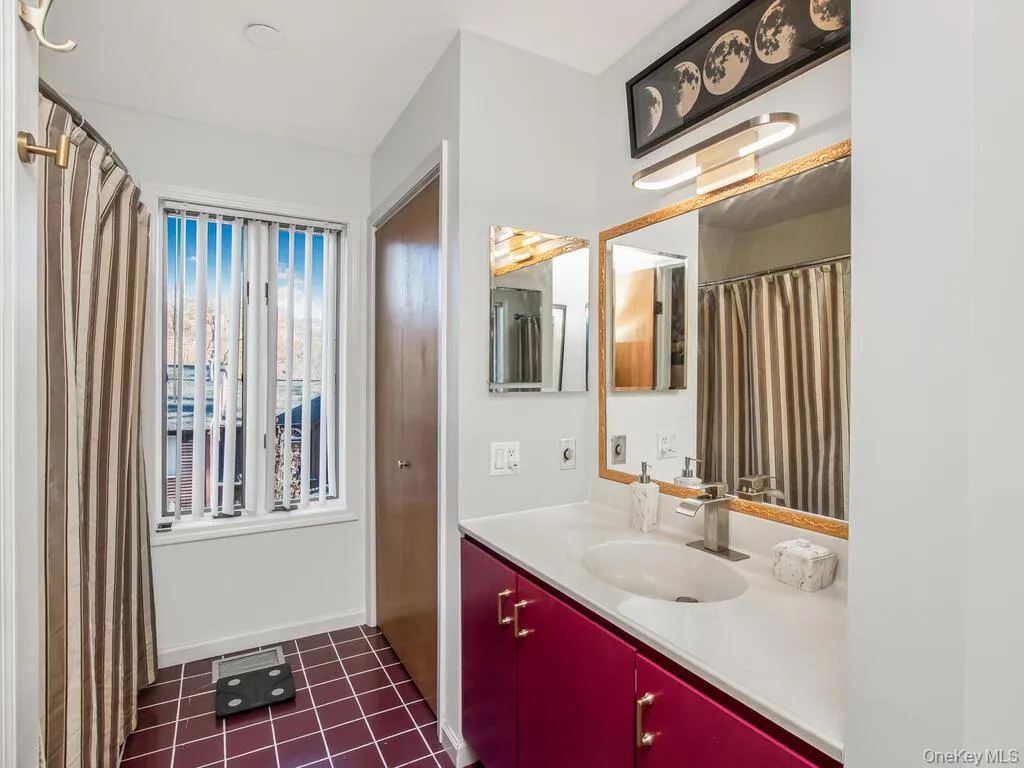 Bathroom with vanity, dark tile patterned flooring, and a shower with curtain Bathroom with vanity, dark tile patterned flooring, and a shower with curtain