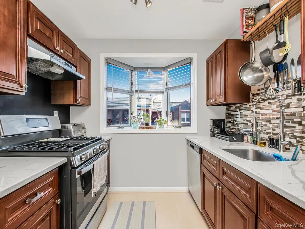 Kitchen with stainless steel appliances, light stone countertops, tasteful backsplash, and under cabinet range hood Kitchen with stainless steel appliances, light stone countertops, tasteful backsplash, and under cabinet range hood