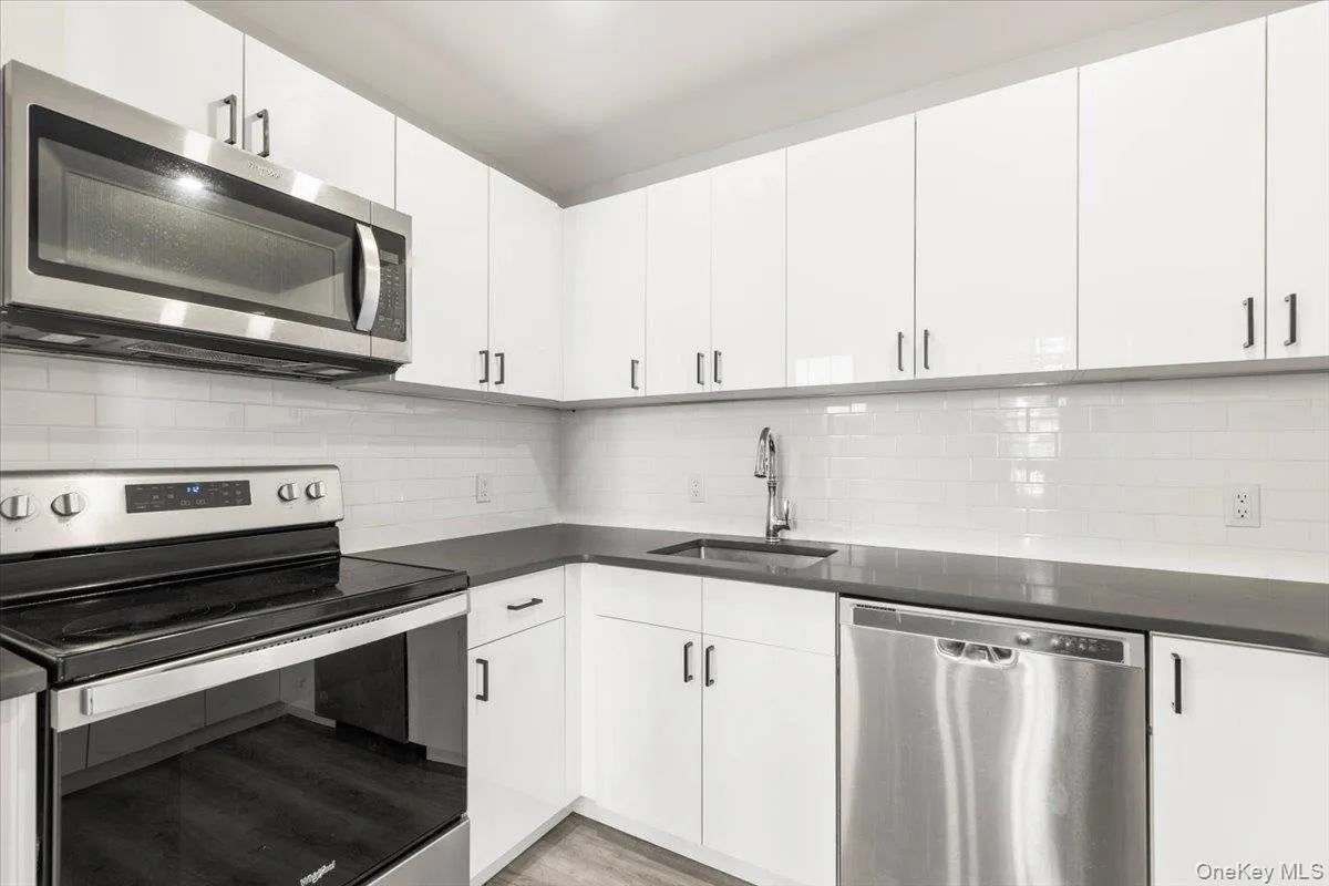 Kitchen with stainless steel appliances, white cabinets, and tasteful backsplash Kitchen with stainless steel appliances, white cabinets, and tasteful backsplash