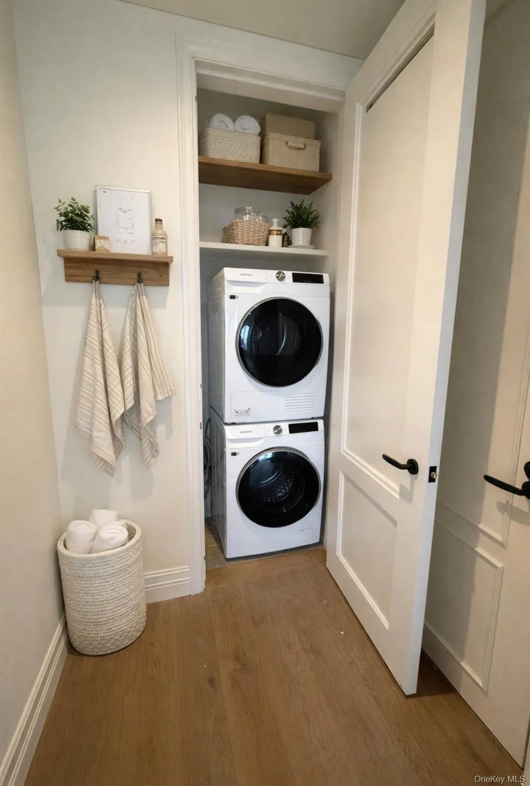 Laundry room with stacked washer and clothes dryer and dark wood-type flooring Laundry room with stacked washer and clothes dryer and dark wood-type flooring
