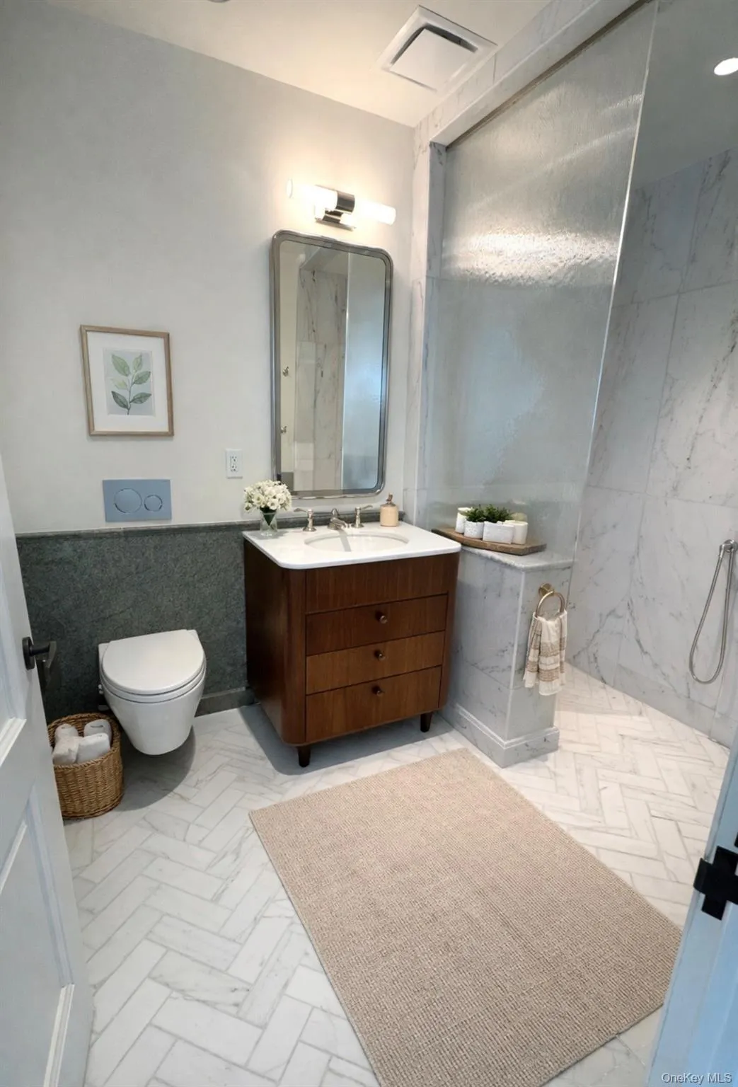 Bathroom with tile walls, vanity, a wainscoted wall, and light marble finish floors Bathroom with tile walls, vanity, a wainscoted wall, and light marble finish floors