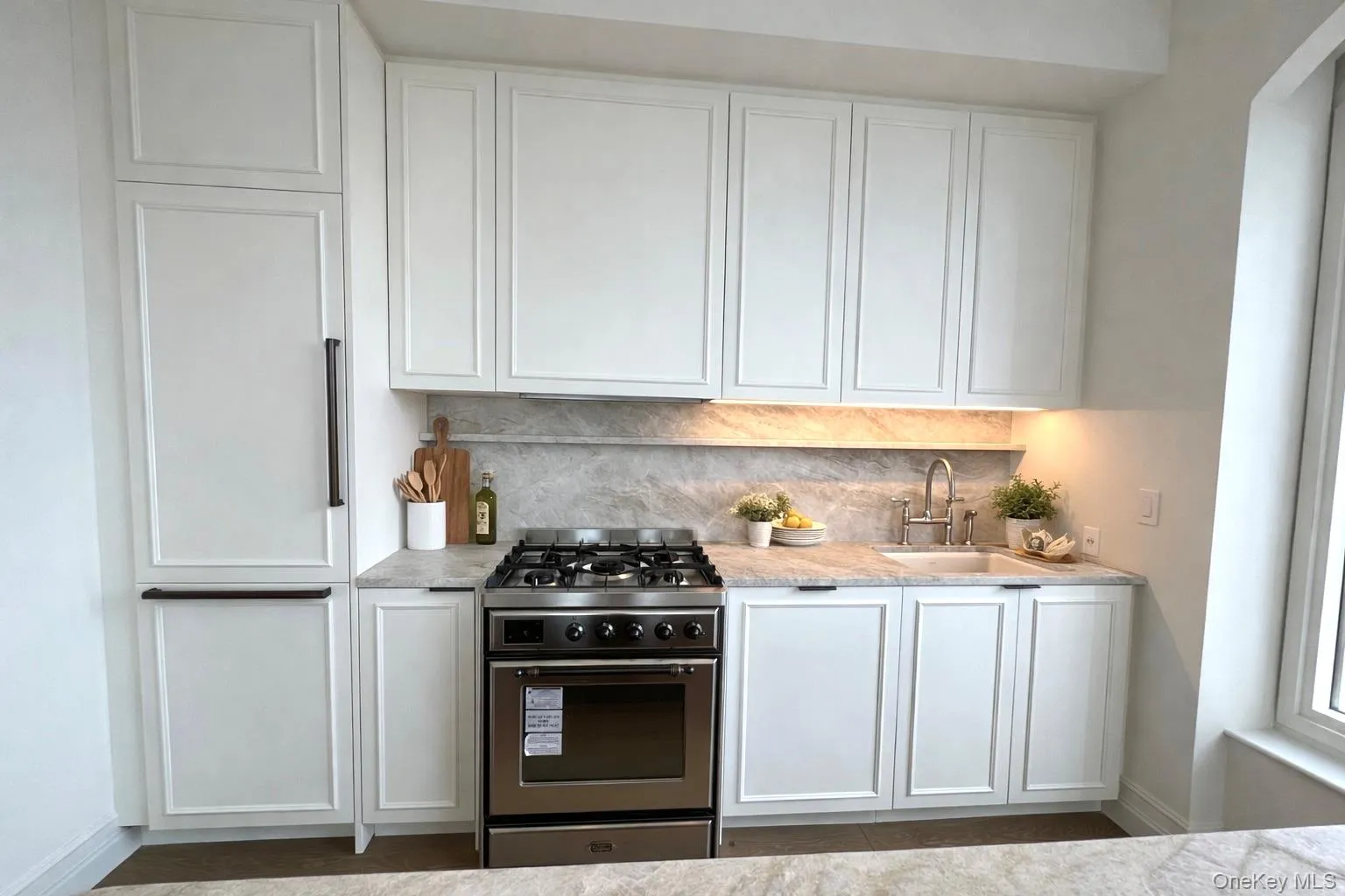 Kitchen featuring white cabinetry, gas stove, and tasteful backsplash Kitchen featuring white cabinetry, gas stove, and tasteful backsplash