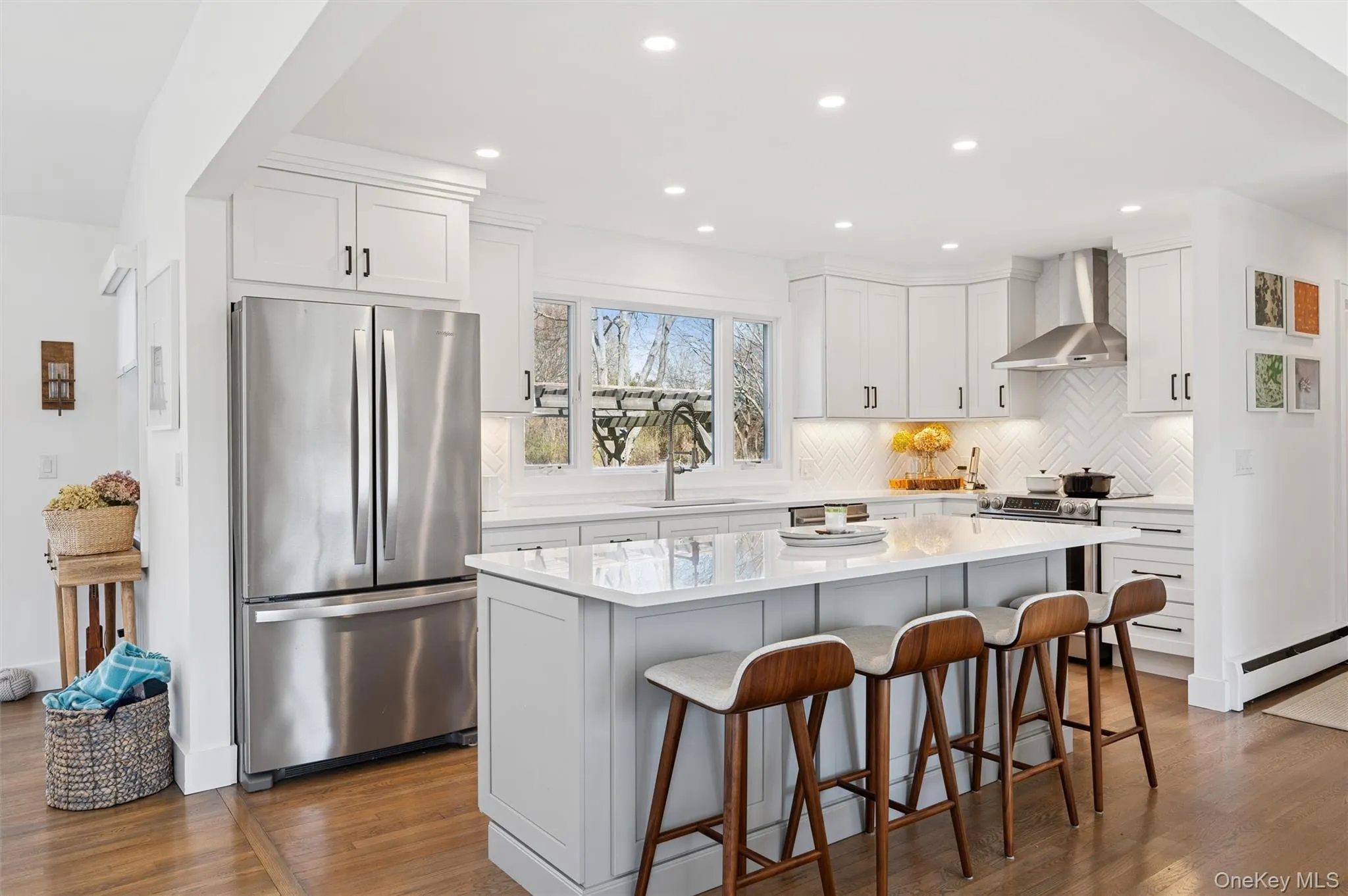 Kitchen featuring wall chimney range hood, freestanding refrigerator, backsplash, dark wood-type flooring, and a sink Kitchen featuring wall chimney range hood, freestanding refrigerator, backsplash, dark wood-type flooring, and a sink