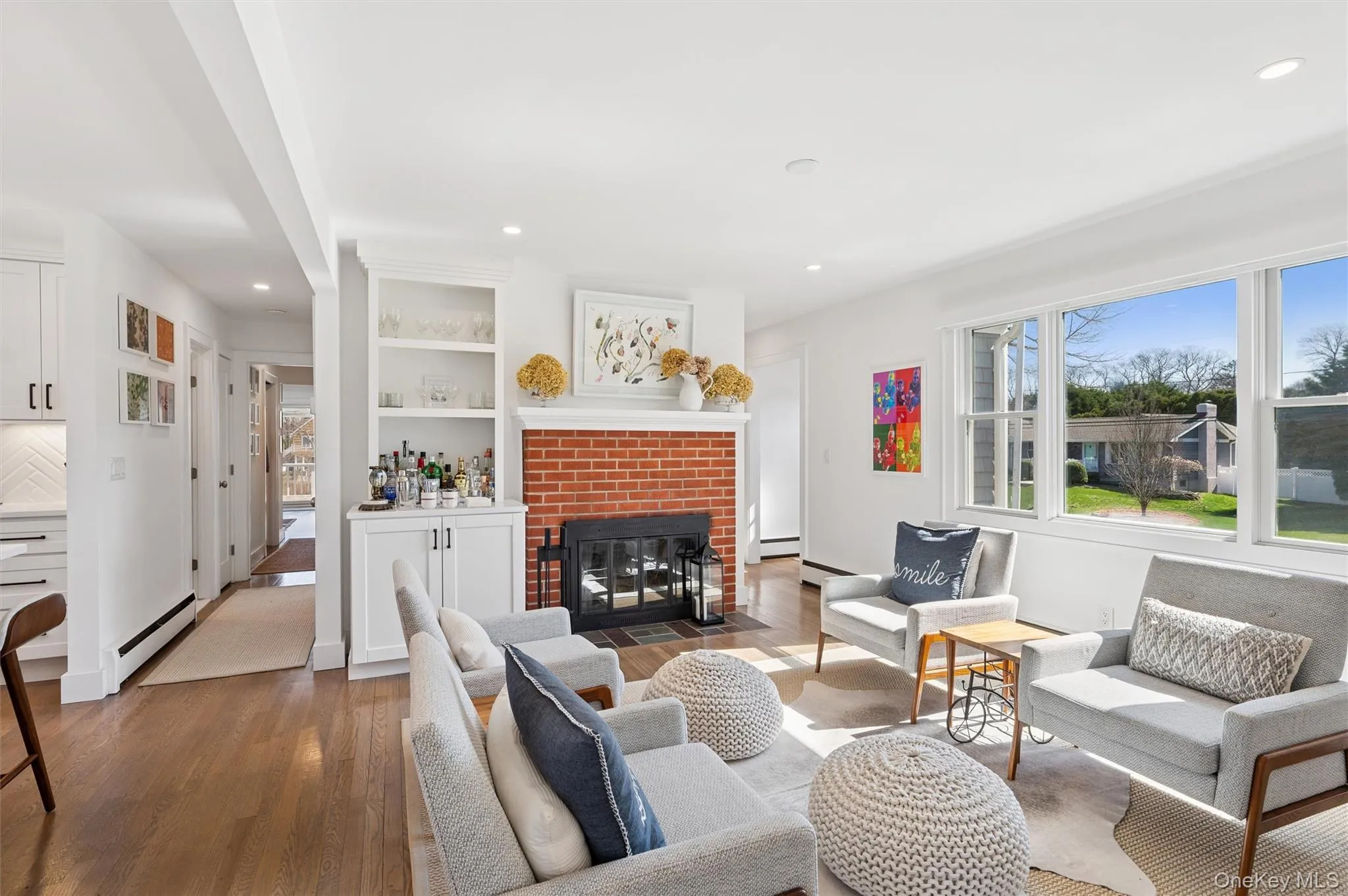 Living room with recessed lighting, a brick fireplace, baseboard heating, and wood finished floors Living room with recessed lighting, a brick fireplace, baseboard heating, and wood finished floors