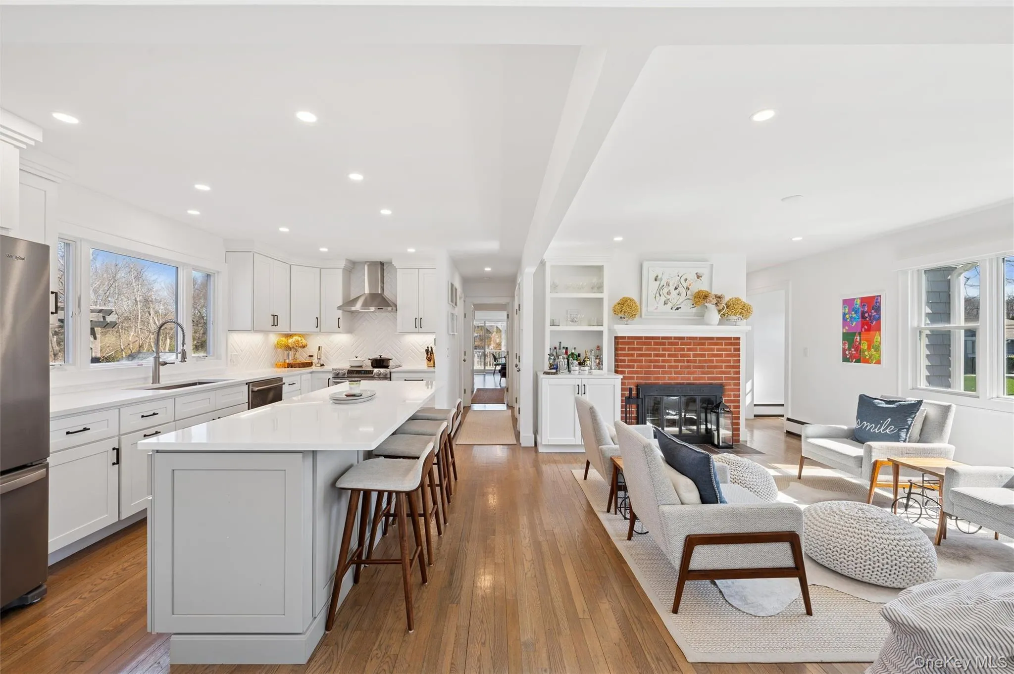 Kitchen with a center island, a sink, wall chimney range hood, a breakfast bar, and freestanding refrigerator Kitchen with a center island, a sink, wall chimney range hood, a breakfast bar, and freestanding refrigerator