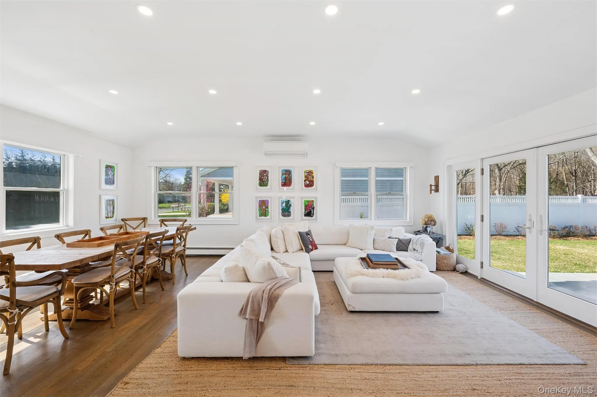 Living room featuring a wall mounted air conditioner, french doors, wood finished floors, and lofted ceiling Living room featuring a wall mounted air conditioner, french doors, wood finished floors, and lofted ceiling
