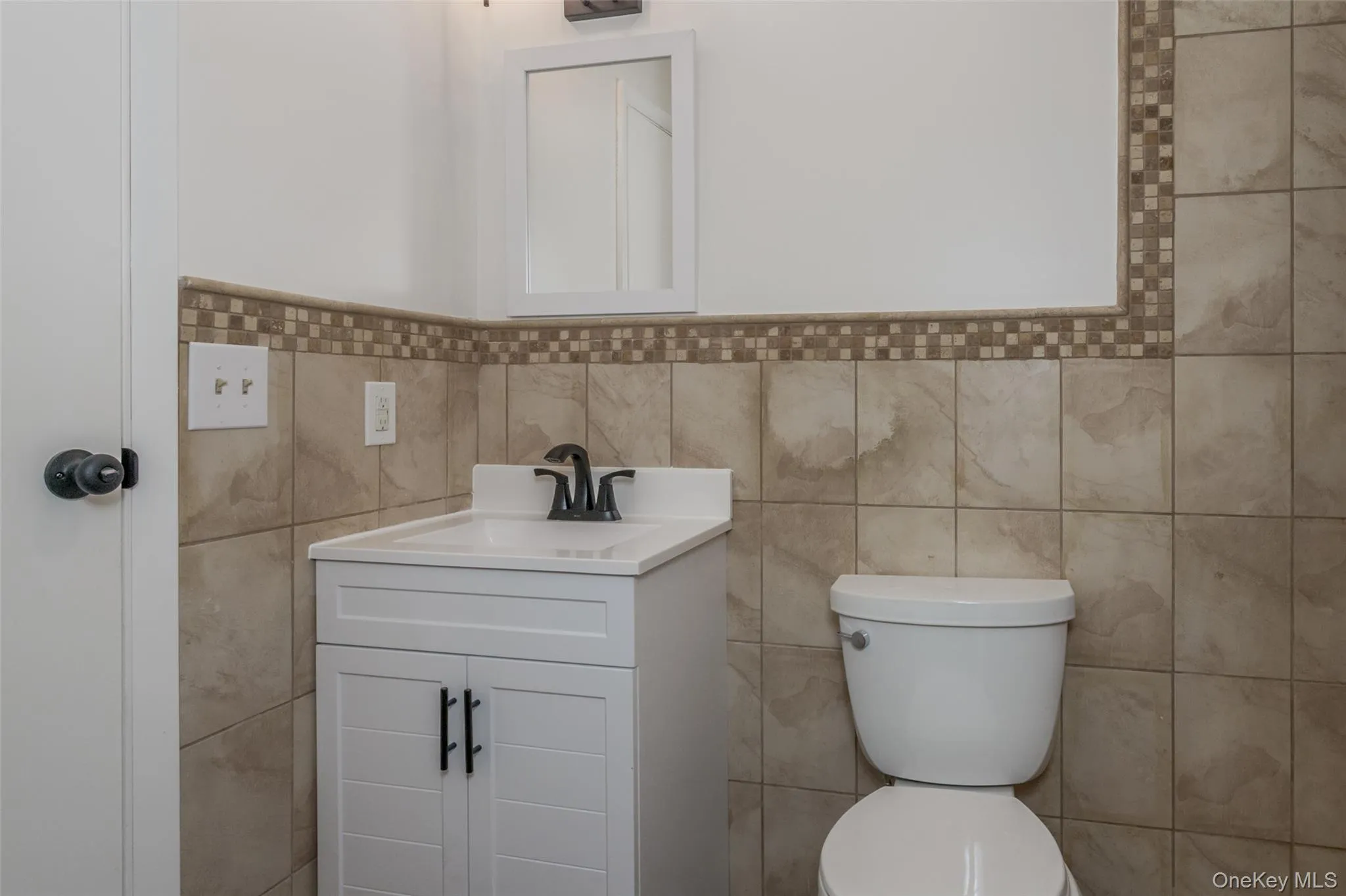 Half bathroom featuring vanity and tile walls Half bathroom featuring vanity and tile walls