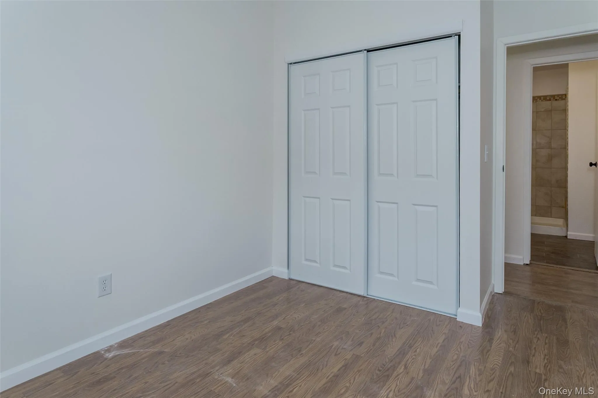 Unfurnished bedroom featuring dark wood-type flooring and a closet Unfurnished bedroom featuring dark wood-type flooring and a closet