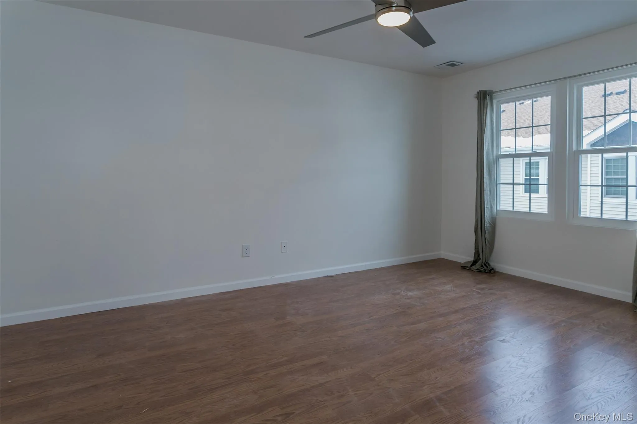 Unfurnished room with dark wood-type flooring and ceiling fan Unfurnished room with dark wood-type flooring and ceiling fan