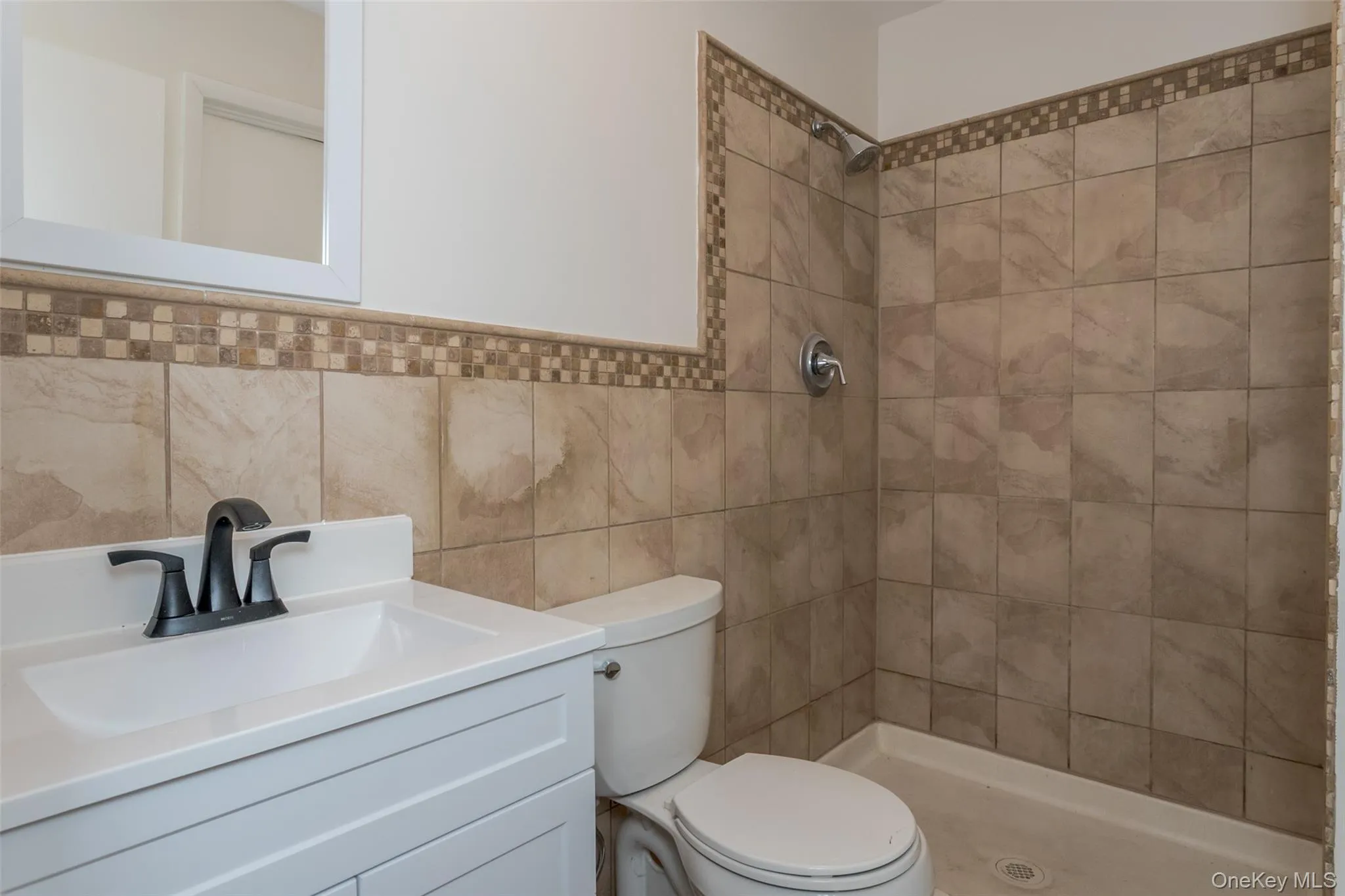 Full bath featuring vanity, tile walls, and a tile shower Full bath featuring vanity, tile walls, and a tile shower