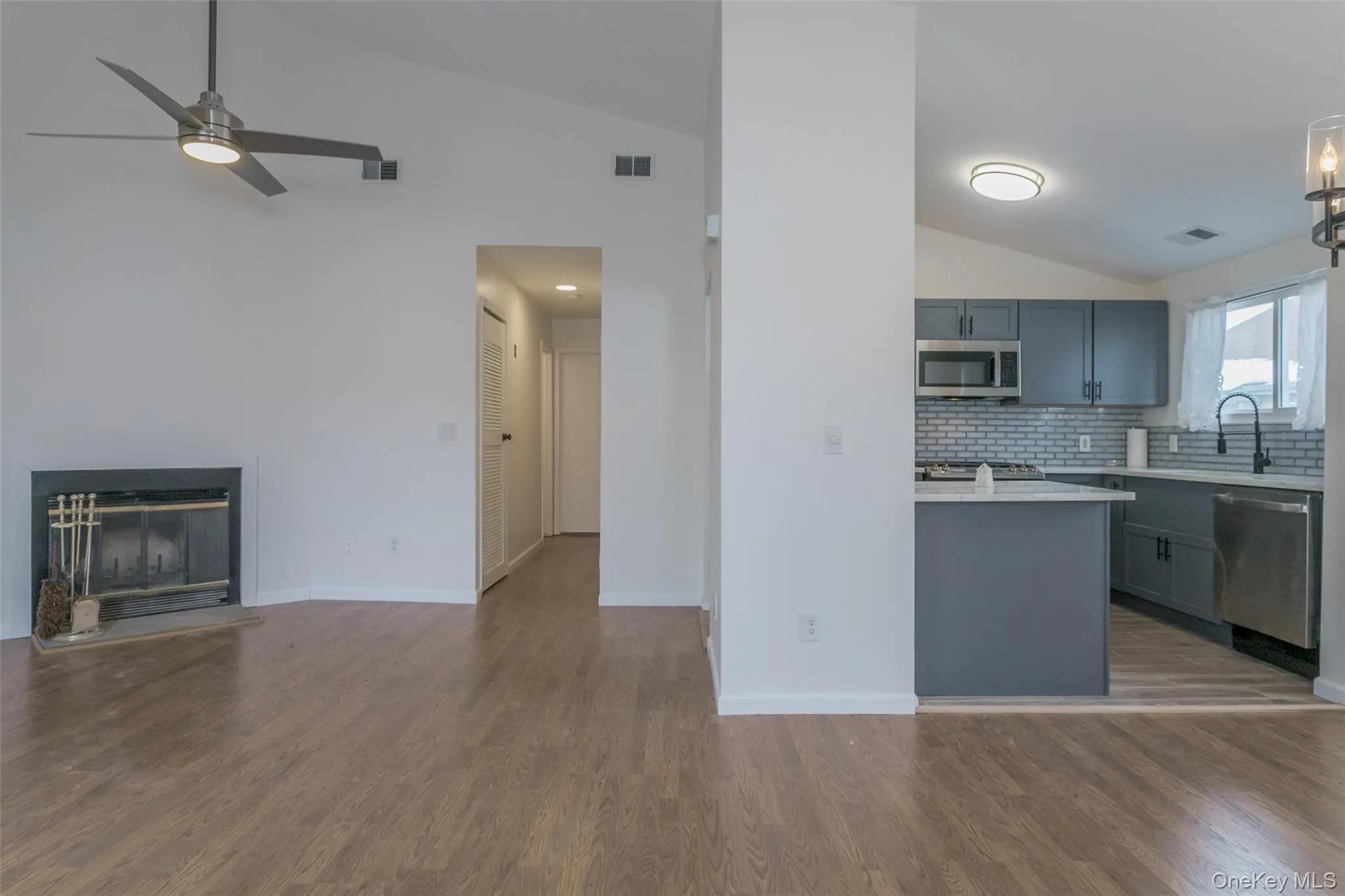 Kitchen featuring vaulted ceiling, open floor plan, appliances with stainless steel finishes, dark wood-type flooring, and backsplash Kitchen featuring vaulted ceiling, open floor plan, appliances with stainless steel finishes, dark wood-type flooring, and backsplash