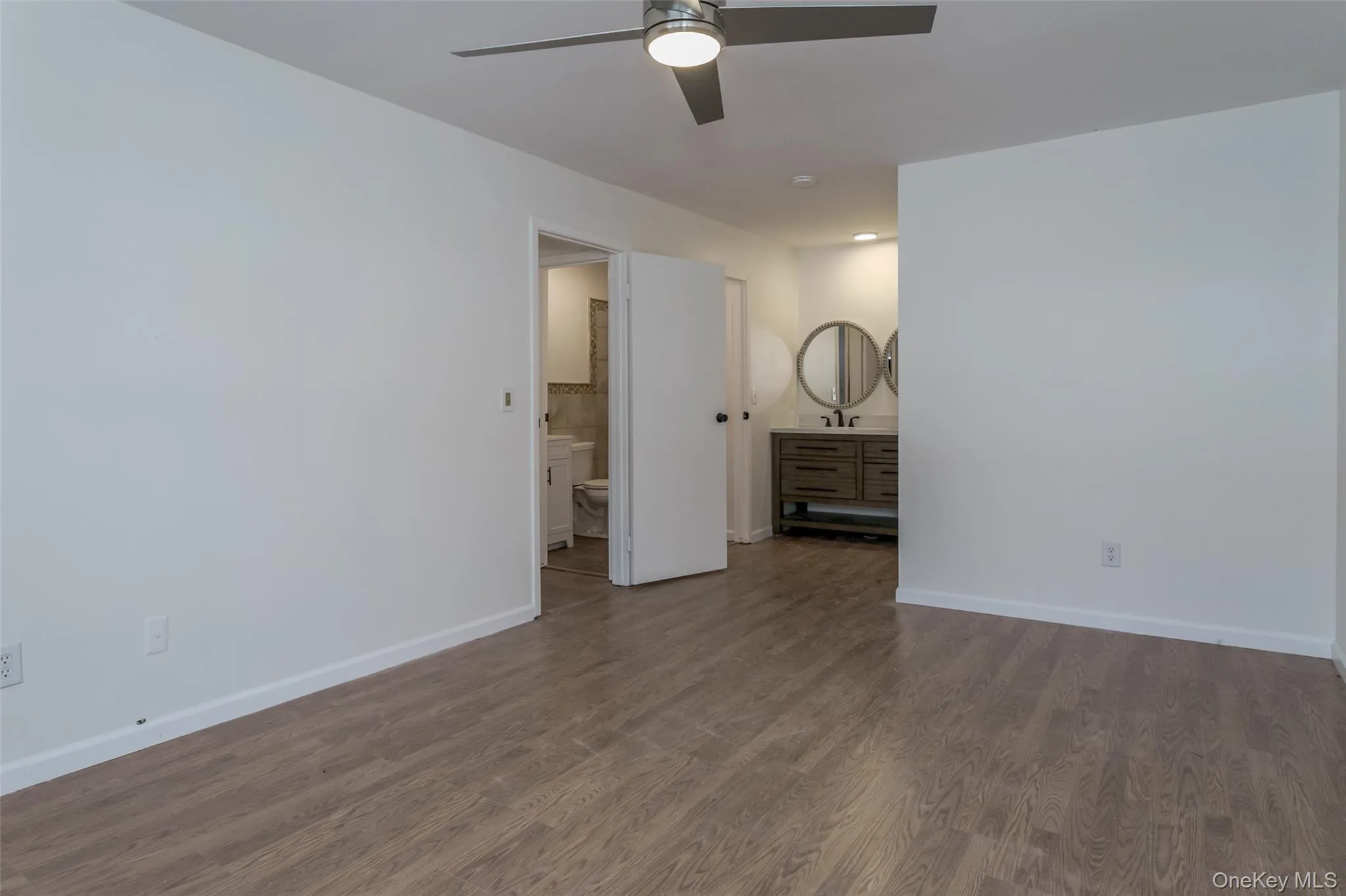 Unfurnished bedroom with wood finished floors, ceiling fan, and ensuite bathroom Unfurnished bedroom with wood finished floors, ceiling fan, and ensuite bathroom