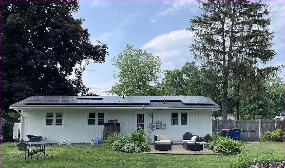 Back of property with outdoor lounge area, a deck, and roof mounted solar panels Back of property with outdoor lounge area, a deck, and roof mounted solar panels