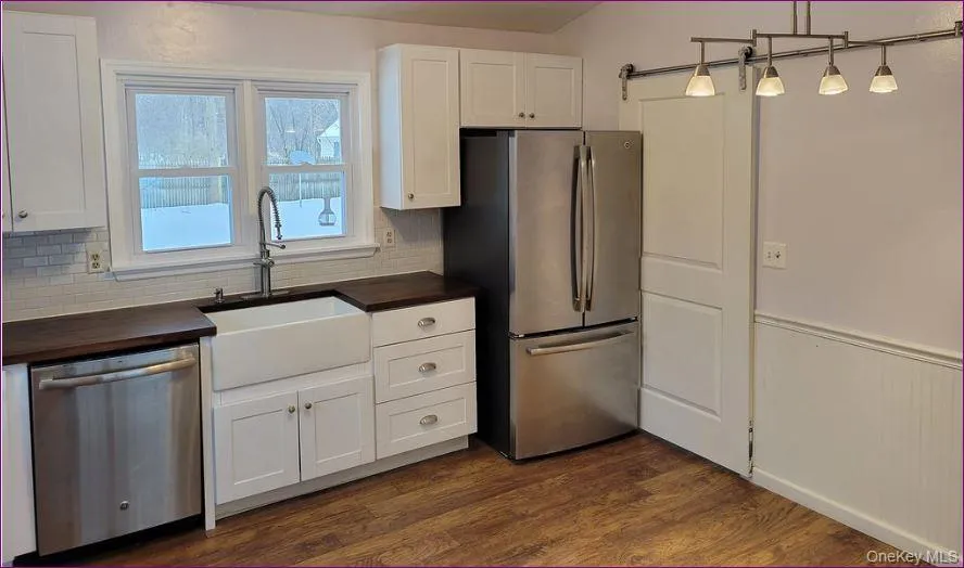 Kitchen with butcher block counters, white cabinetry, appliances with stainless steel finishes, dark wood-style flooring, and pendant lighting Kitchen with butcher block counters, white cabinetry, appliances with stainless steel finishes, dark wood-style flooring, and pendant lighting