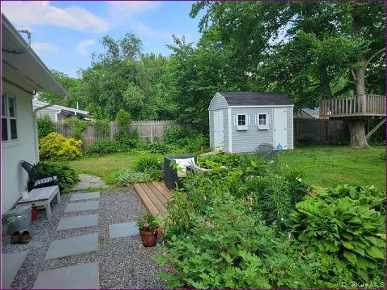 Fenced backyard featuring a deck and a storage unit Fenced backyard featuring a deck and a storage unit