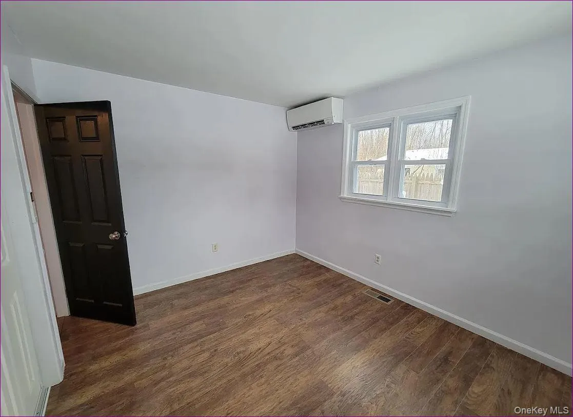 Empty room featuring dark wood finished floors and a wall mounted AC Empty room featuring dark wood finished floors and a wall mounted AC