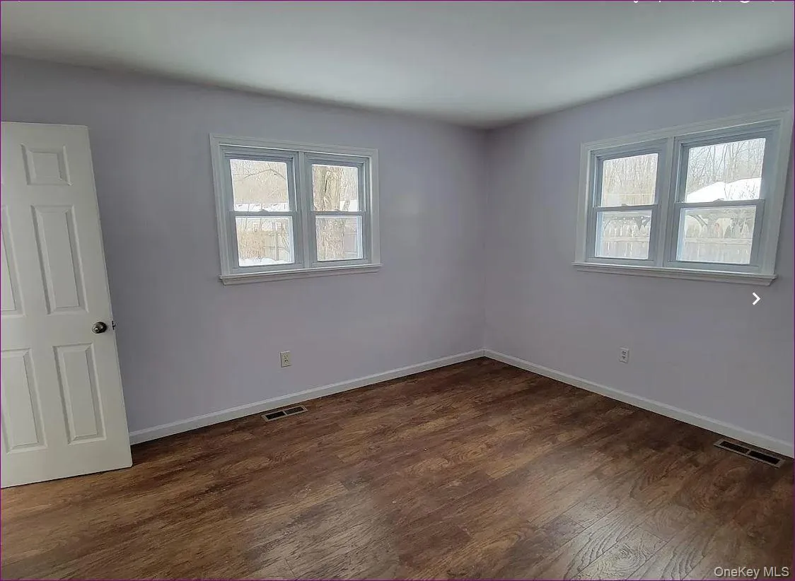 Empty room featuring dark wood finished floors and baseboards Empty room featuring dark wood finished floors and baseboards