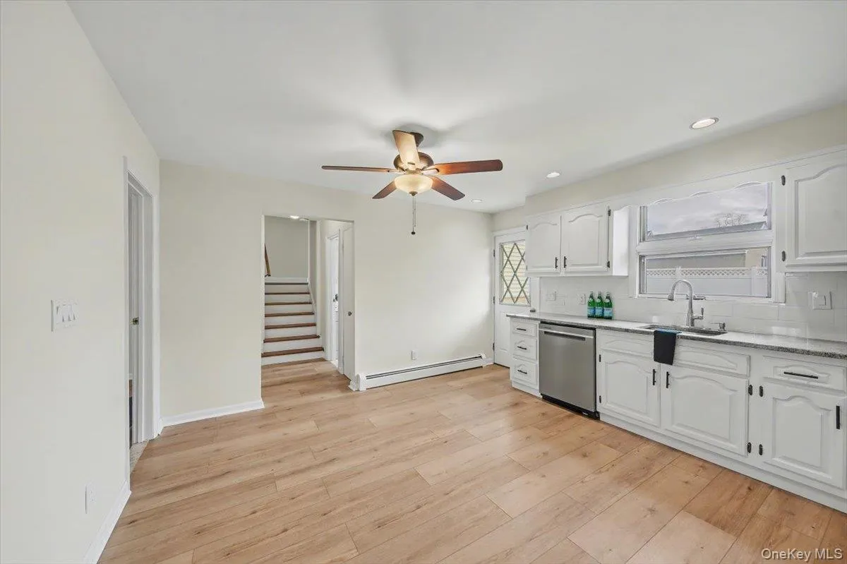 Kitchen featuring white cabinetry, dishwasher, a baseboard heating unit, tasteful backsplash, and ceiling fan Kitchen featuring white cabinetry, dishwasher, a baseboard heating unit, tasteful backsplash, and ceiling fan