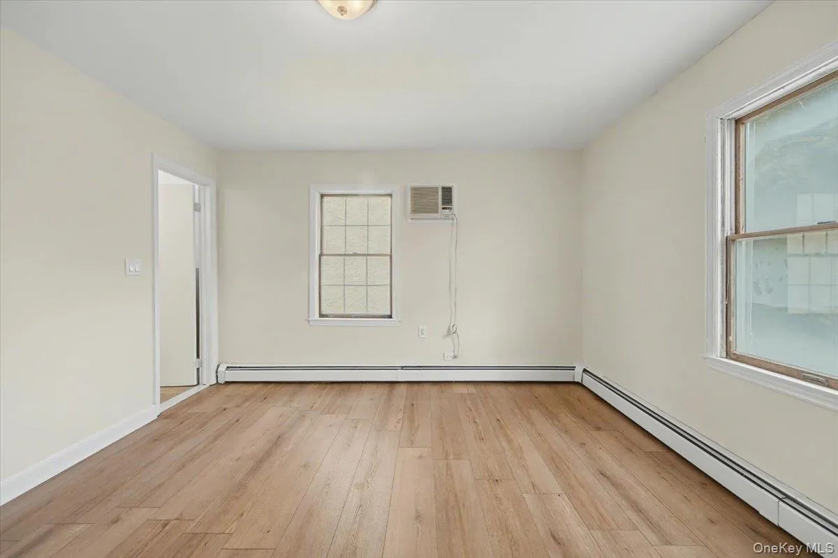 Unfurnished room featuring a baseboard radiator and light wood-type flooring Unfurnished room featuring a baseboard radiator and light wood-type flooring