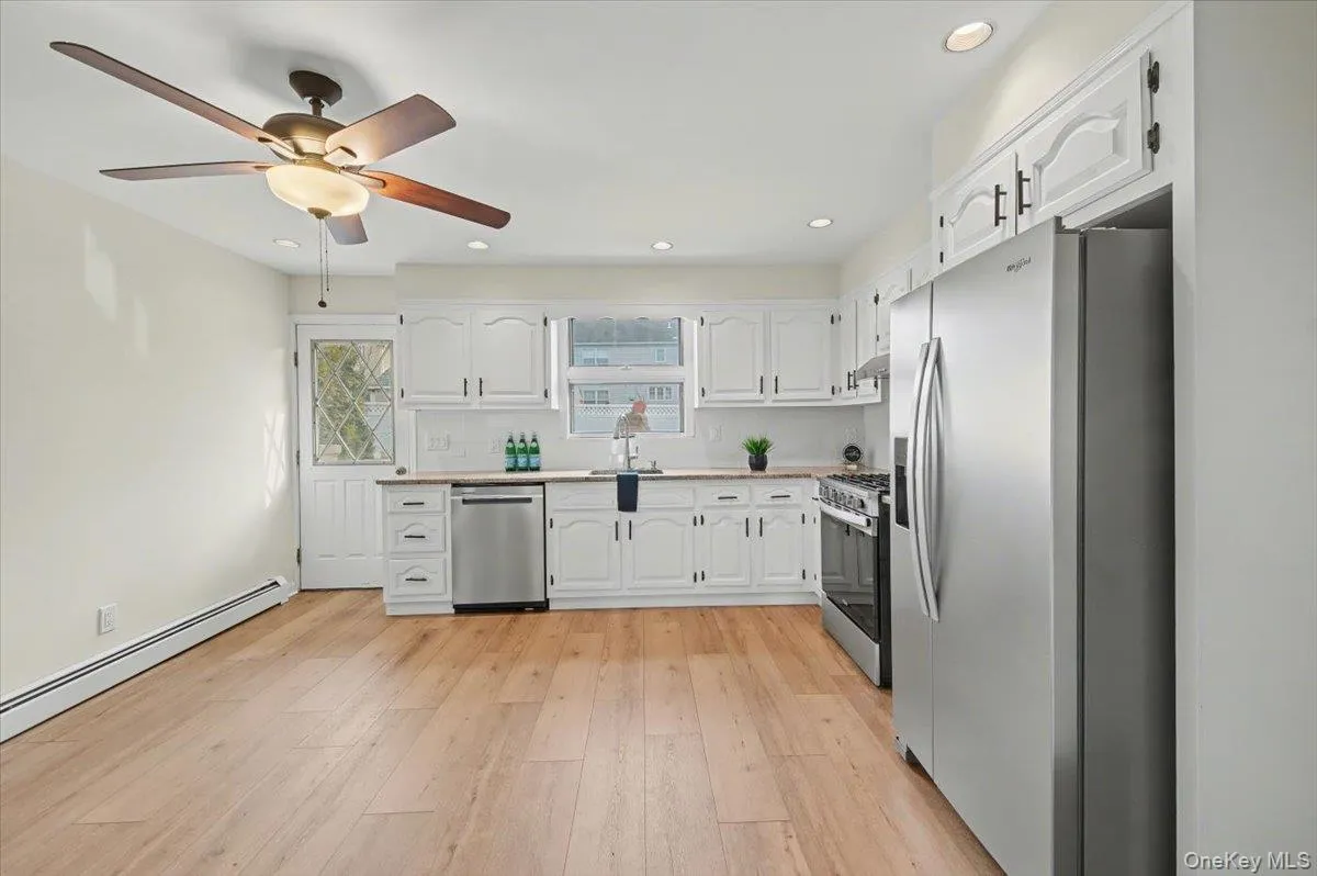 Kitchen featuring appliances with stainless steel finishes, white cabinets, light countertops, light wood-style floors, and ceiling fan Kitchen featuring appliances with stainless steel finishes, white cabinets, light countertops, light wood-style floors, and ceiling fan