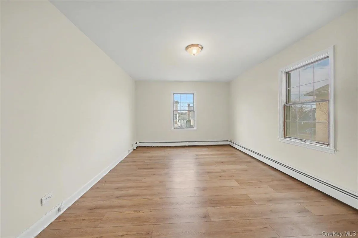 Empty room with baseboard heating and light wood-style floors Empty room with baseboard heating and light wood-style floors