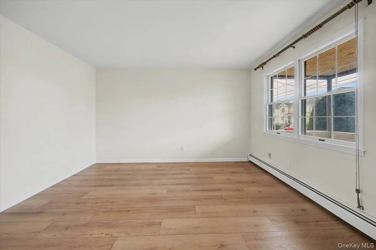 Unfurnished room featuring a baseboard heating unit and light wood finished floors Unfurnished room featuring a baseboard heating unit and light wood finished floors