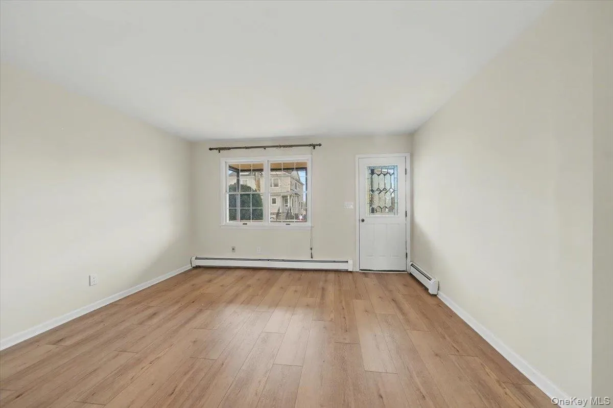 Empty room with light wood finished floors and a baseboard heating unit Empty room with light wood finished floors and a baseboard heating unit