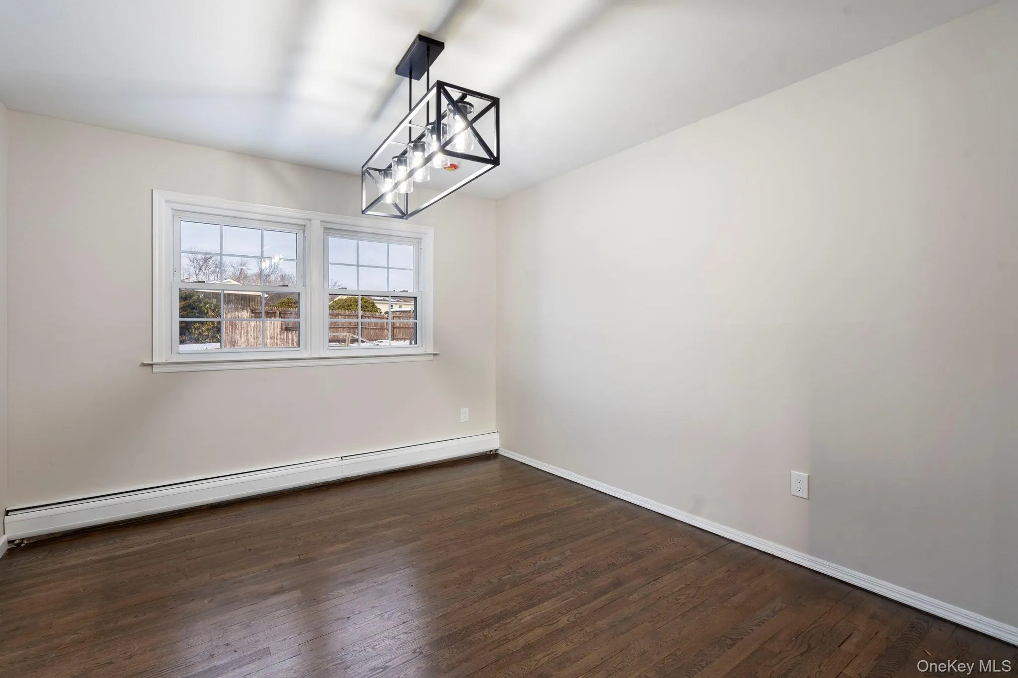 Unfurnished room featuring a baseboard radiator and dark wood-type flooring Unfurnished room featuring a baseboard radiator and dark wood-type flooring
