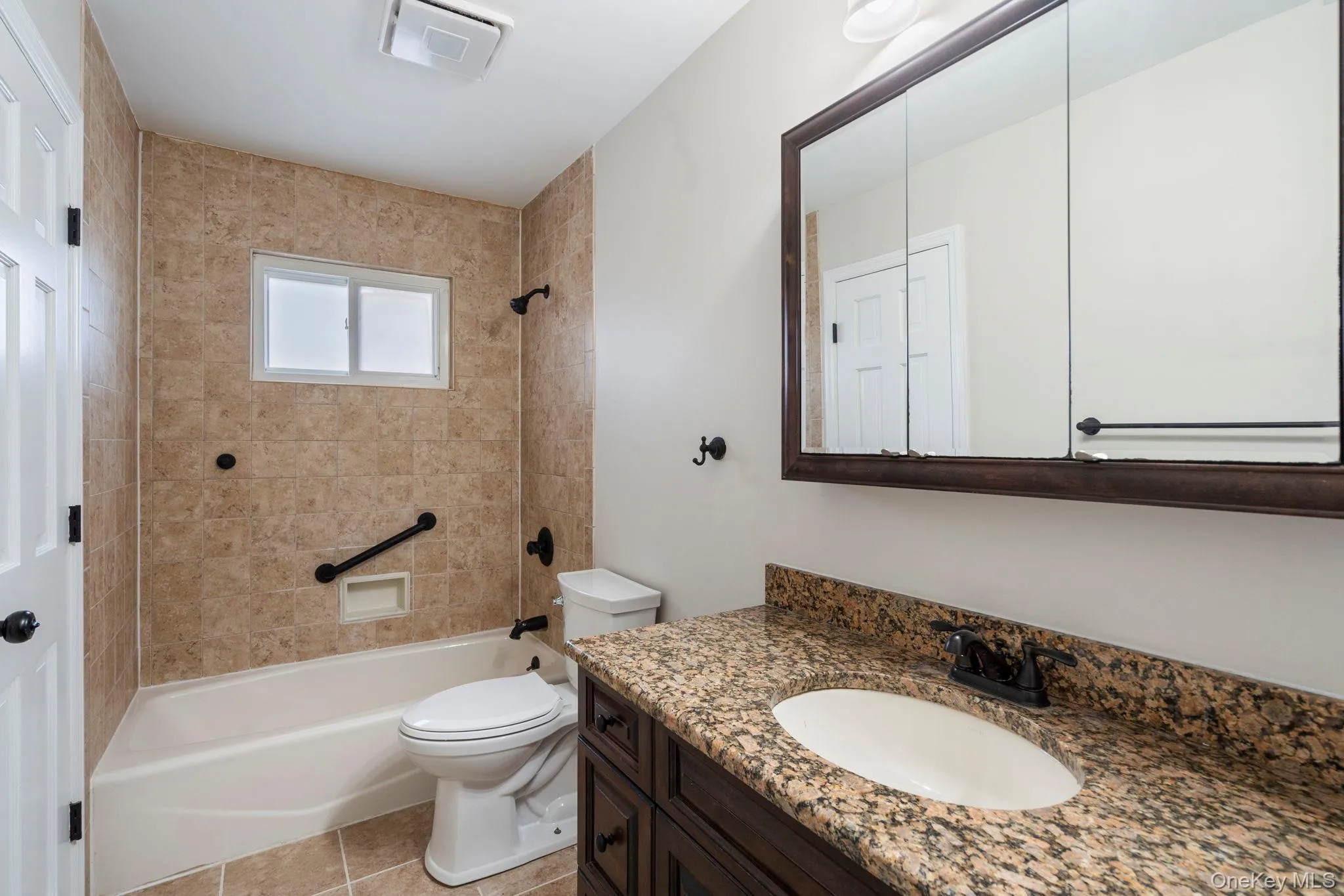 Full bathroom featuring tub / shower combination, vanity, and light tile patterned floors Full bathroom featuring tub / shower combination, vanity, and light tile patterned floors