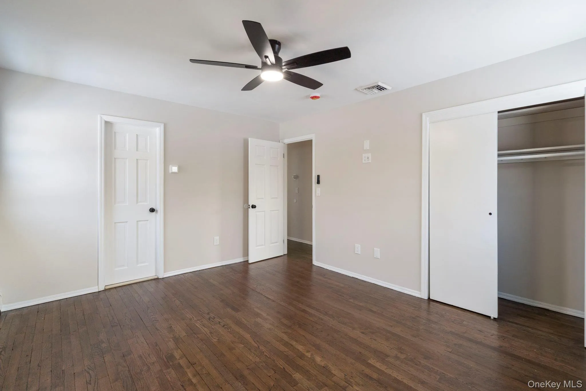 Unfurnished bedroom featuring dark wood finished floors, a ceiling fan, and a closet Unfurnished bedroom featuring dark wood finished floors, a ceiling fan, and a closet