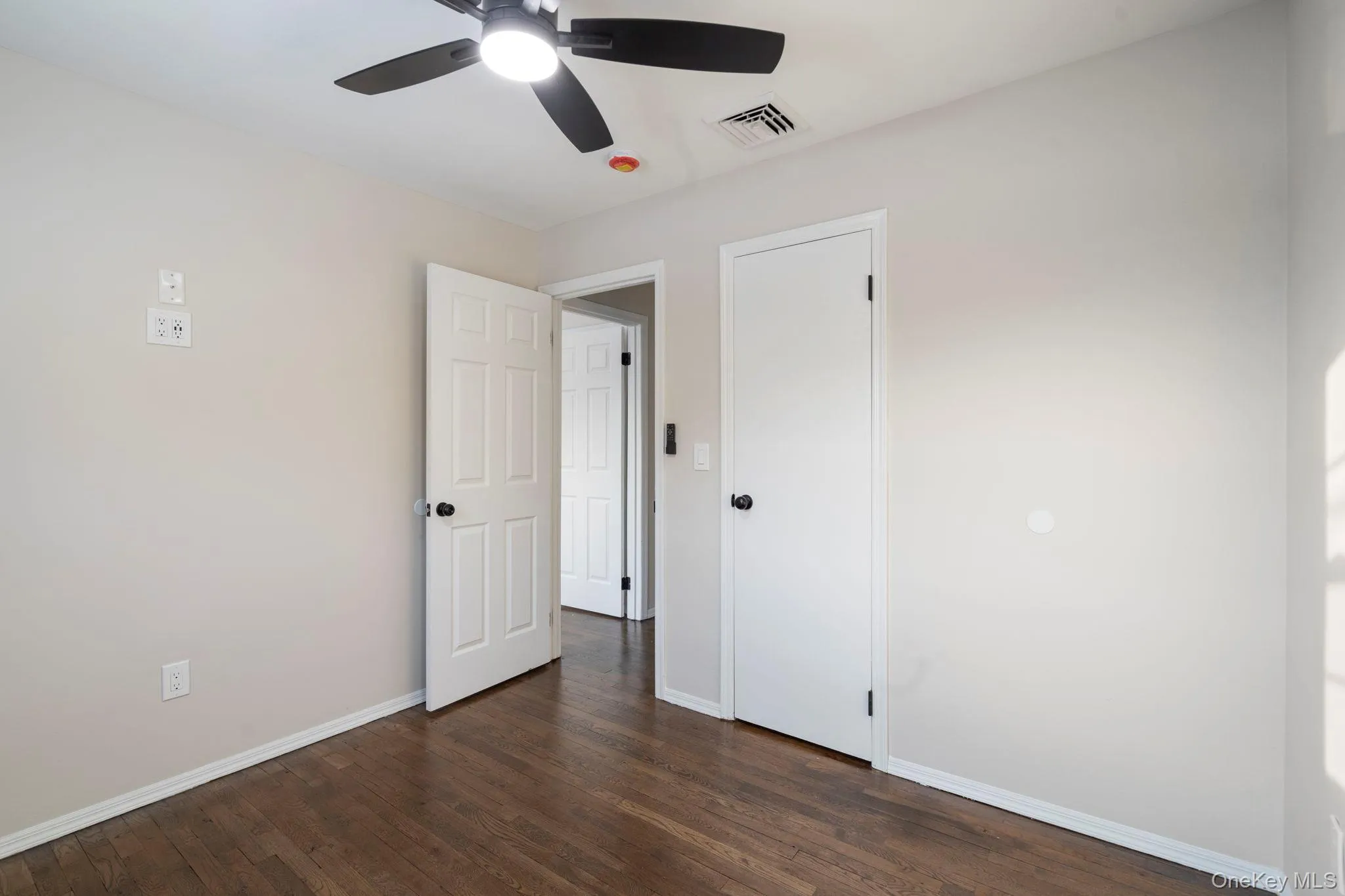 Unfurnished bedroom with dark wood-style floors and a ceiling fan Unfurnished bedroom with dark wood-style floors and a ceiling fan