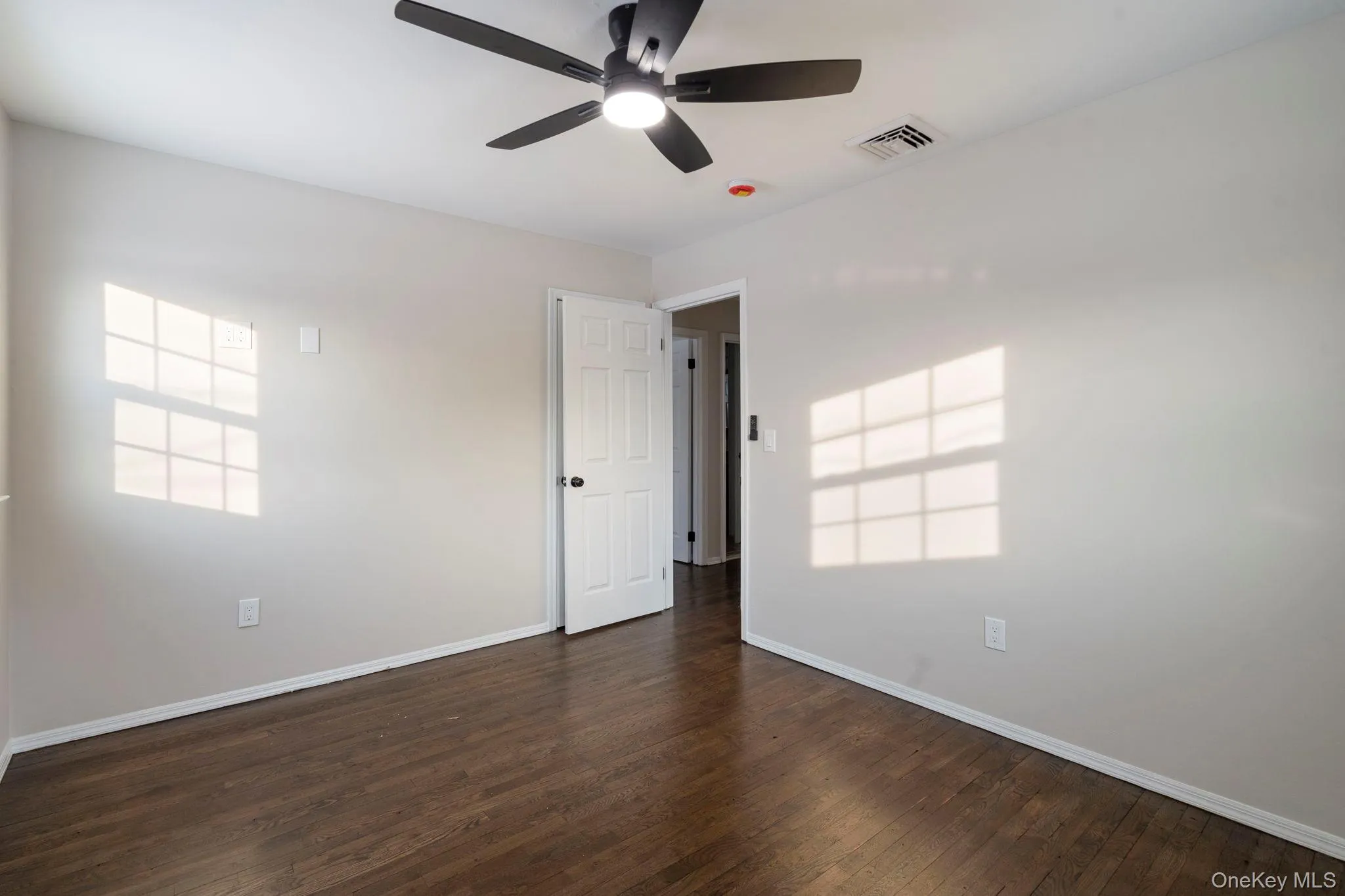 Spare room with dark wood finished floors and a ceiling fan Spare room with dark wood finished floors and a ceiling fan