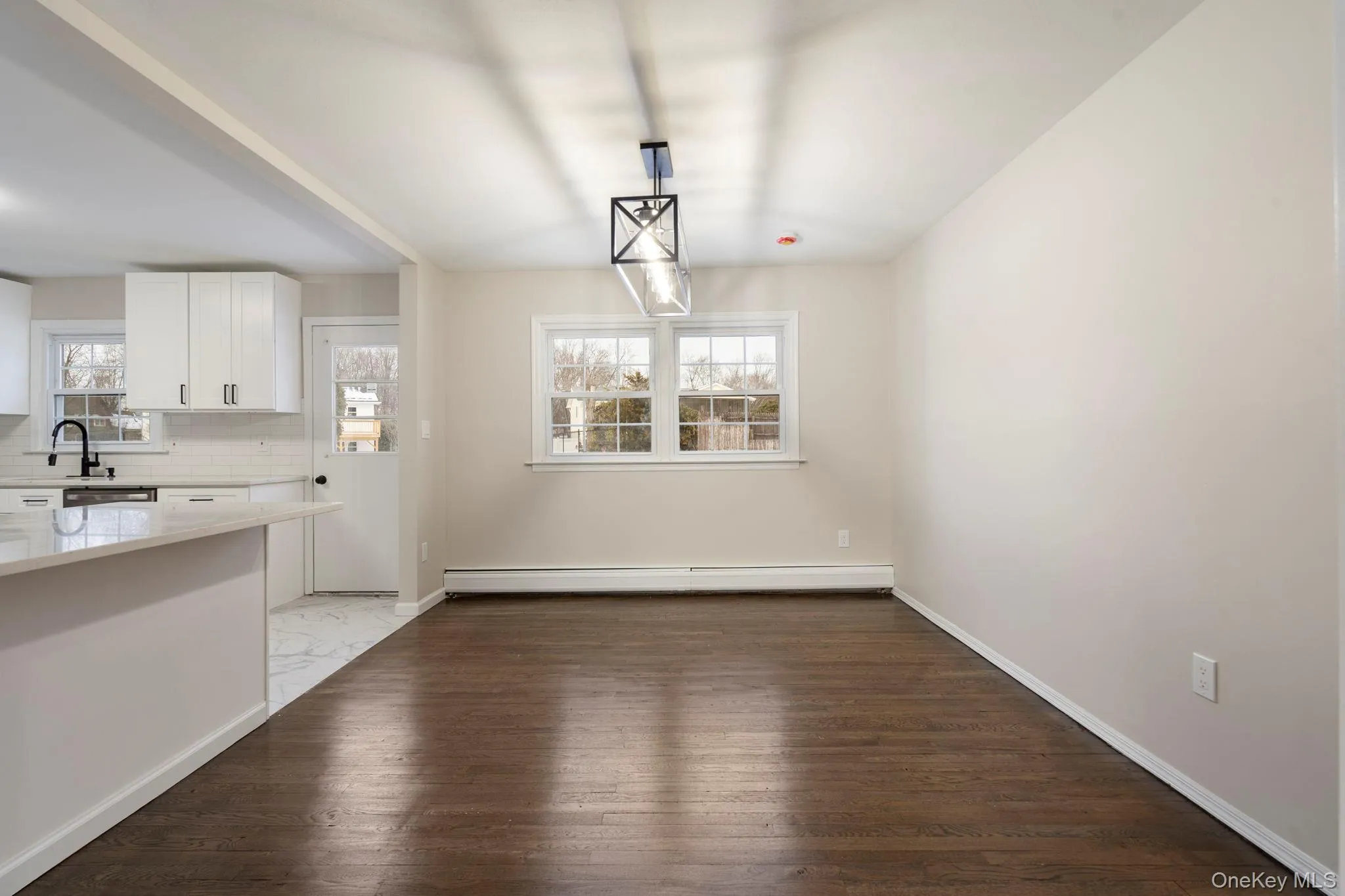 Unfurnished dining area featuring dark wood finished floors and baseboard heating Unfurnished dining area featuring dark wood finished floors and baseboard heating