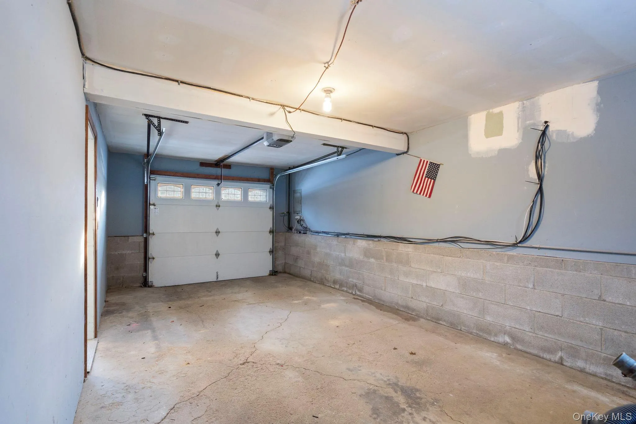 Garage featuring concrete block wall and a garage door opener Garage featuring concrete block wall and a garage door opener