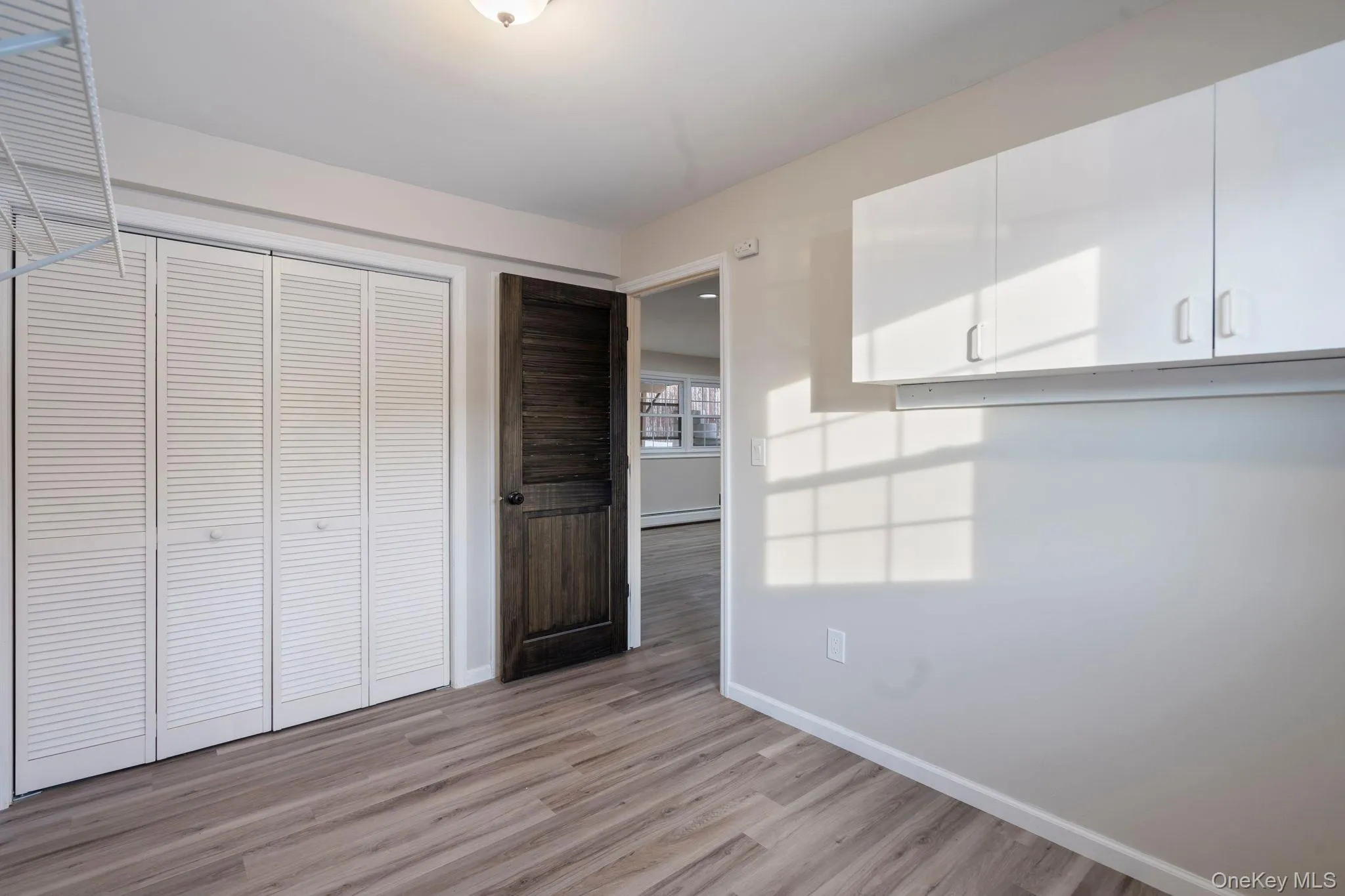 Unfurnished bedroom featuring light wood-type flooring, a closet, and a baseboard radiator Unfurnished bedroom featuring light wood-type flooring, a closet, and a baseboard radiator