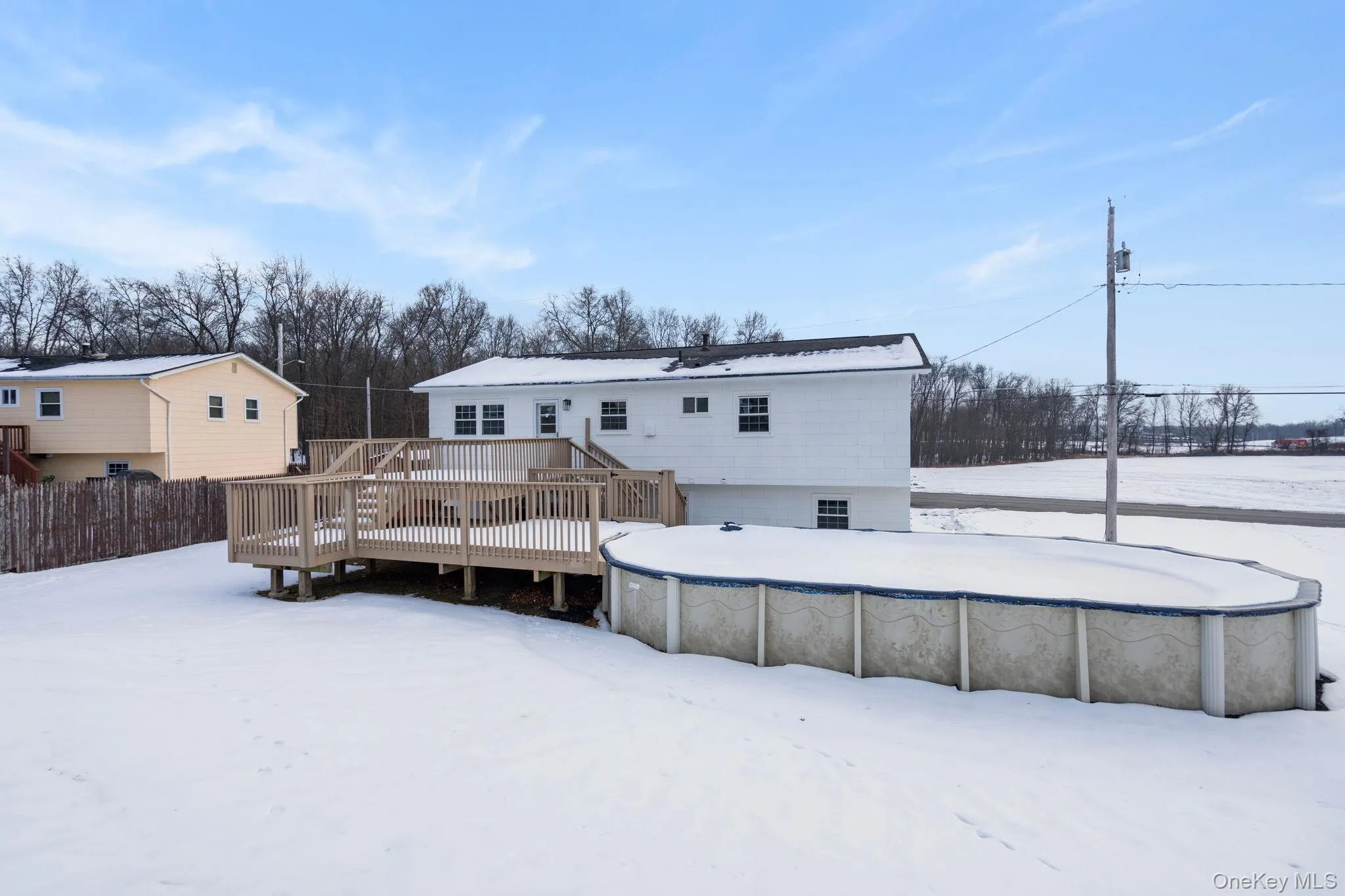 Snow covered rear of property featuring a wooden deck Snow covered rear of property featuring a wooden deck